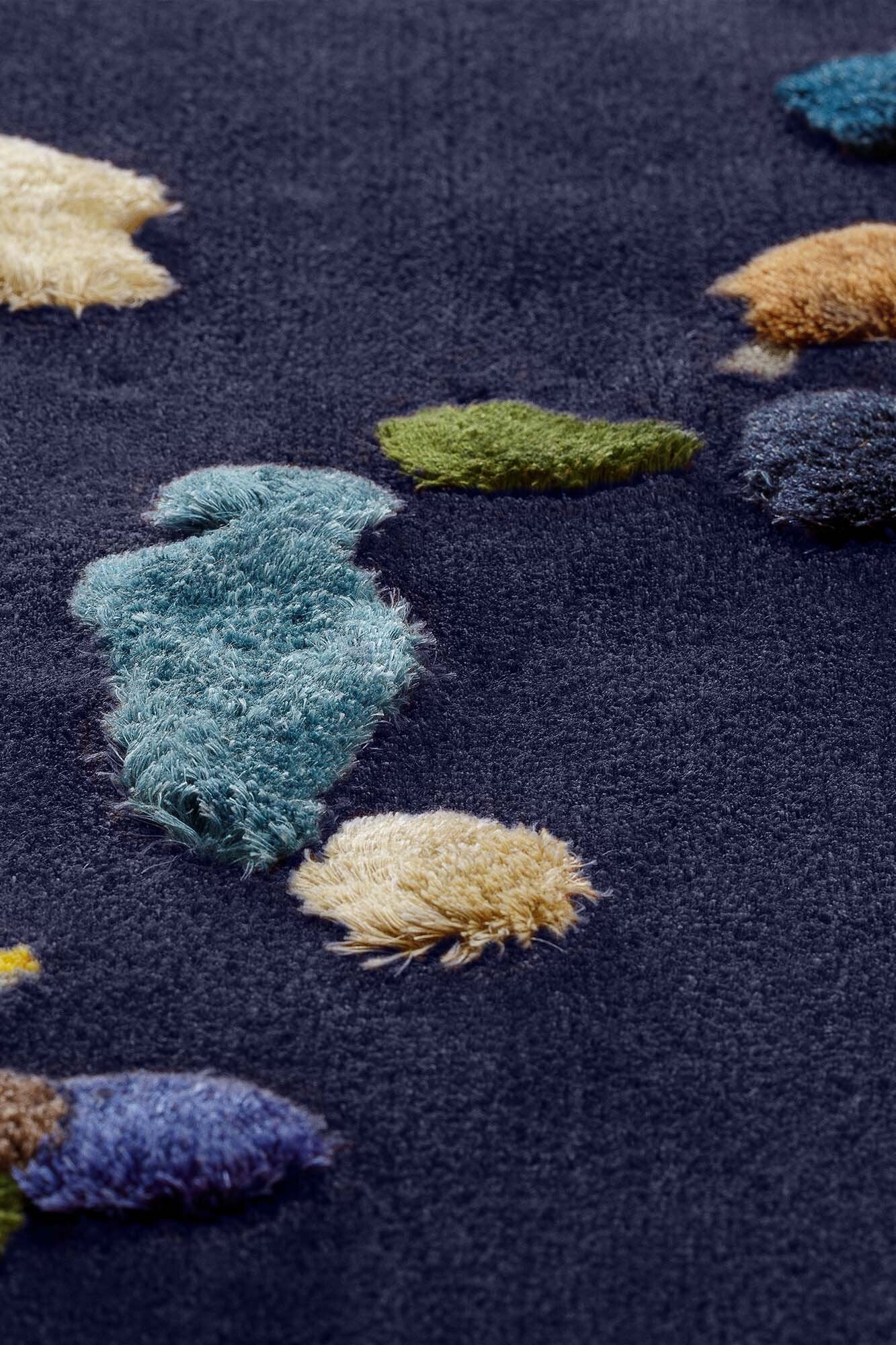 A vibrant Chaos Rug designed by Audronė Drungilaitė, showcasing unique colors and patterns made from leftover yarn, available in dark blue and caramel brown.