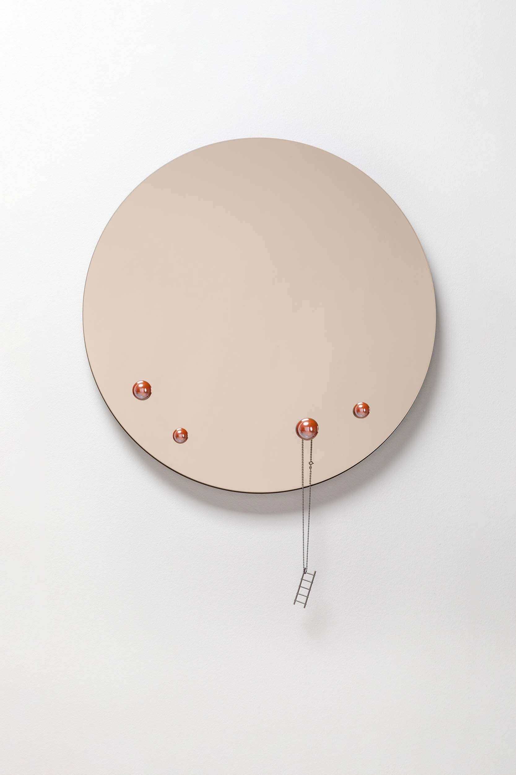 The Dew Mirror designed by Rasa Balaišė, featuring a reflective surface and four decorative glass droplets, available in bronze, dark grey, and clear finishes.