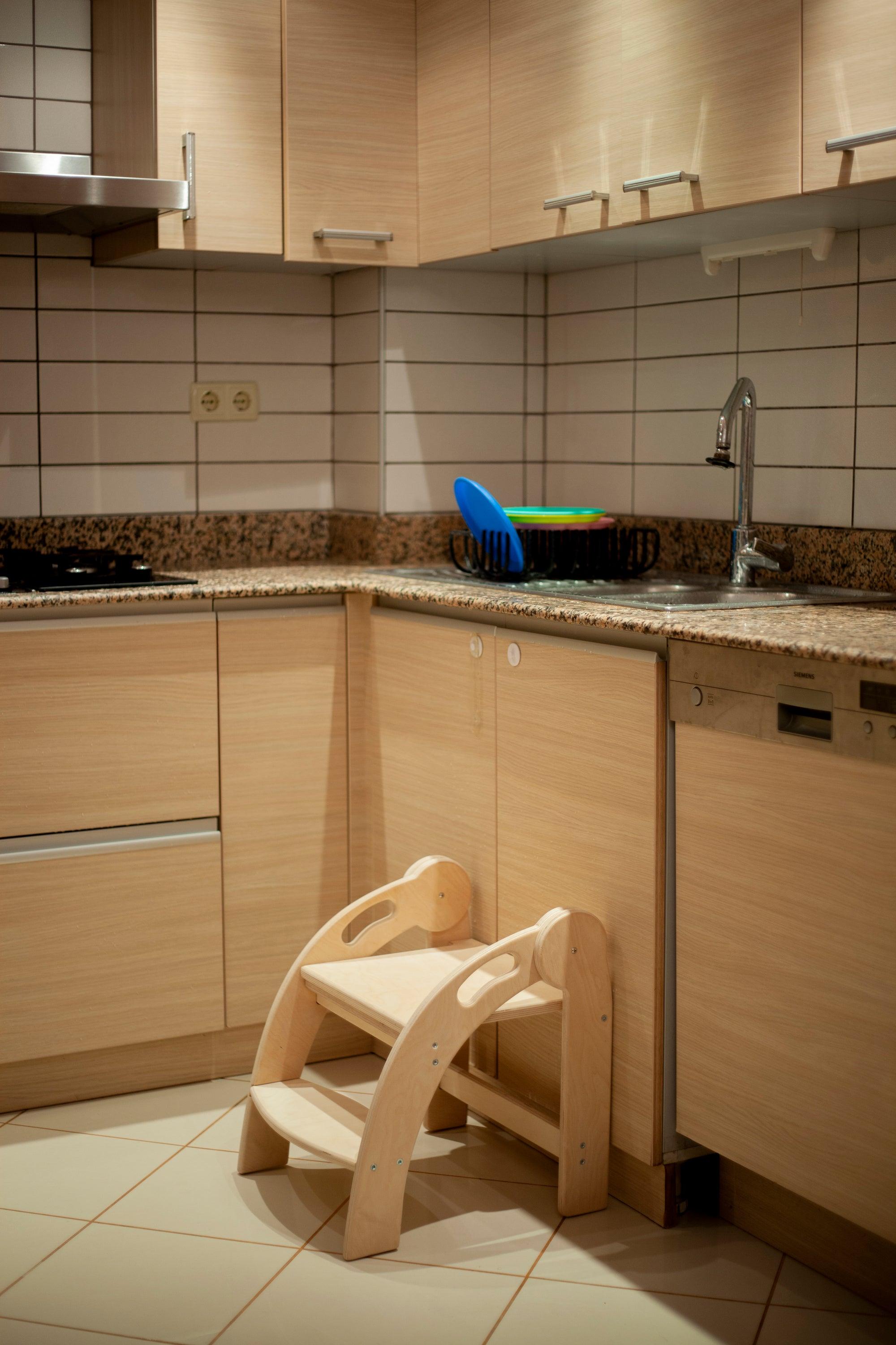 Foldable Montessori Kitchen Step Stool made of natural birch plywood, featuring two steps for children to reach higher surfaces safely.