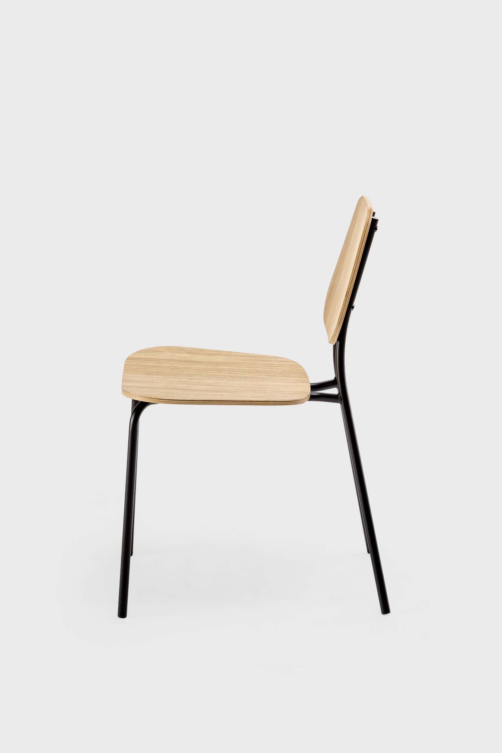 The Hoya Chair features a sleek black metal frame with a veneered plywood seat and backrest, available in natural oil, black, and walnut finishes, showcasing its modern design.