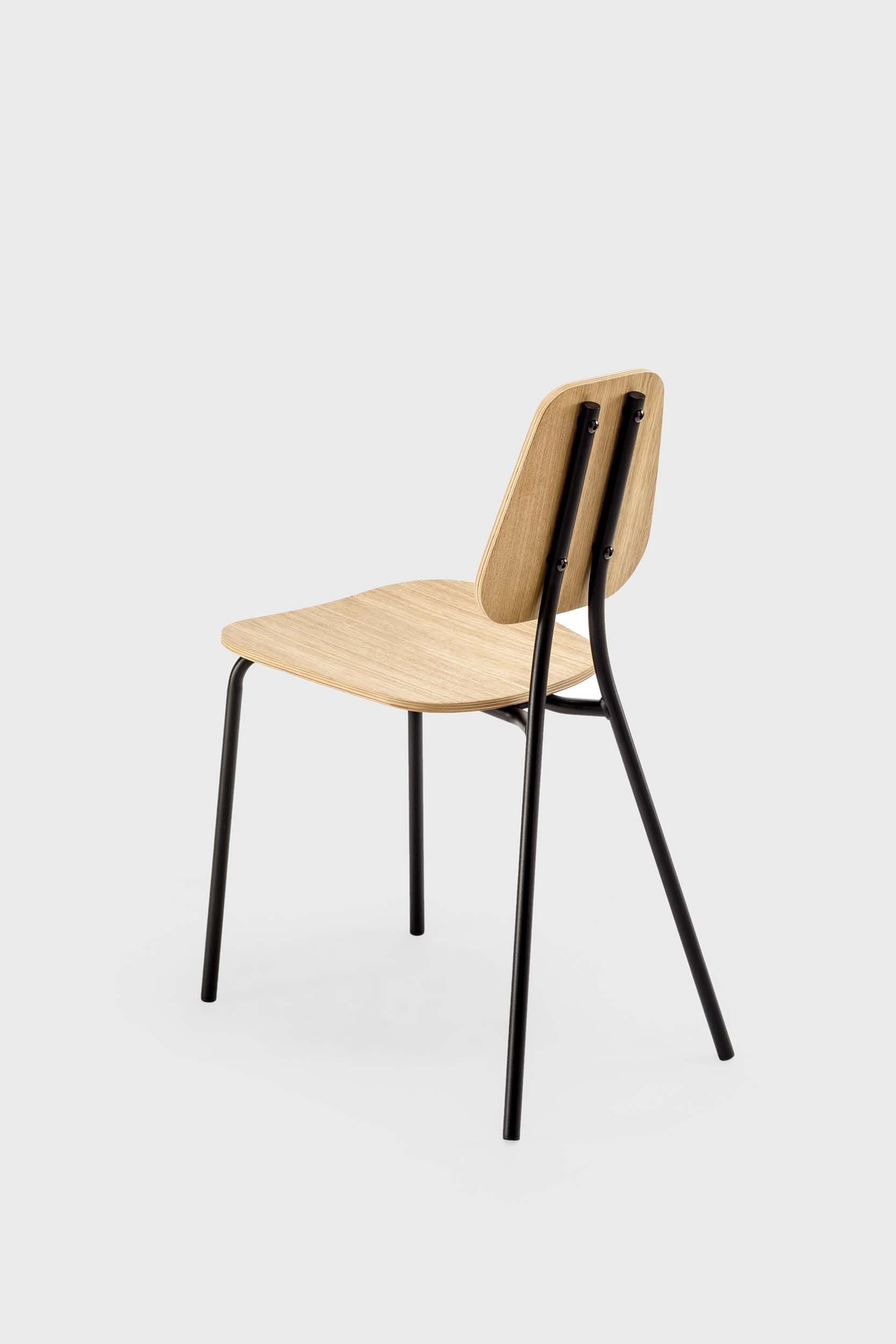 The Hoya Chair features a sleek black metal frame with a veneered plywood seat and backrest, available in natural oil, black, and walnut finishes, showcasing its modern design.