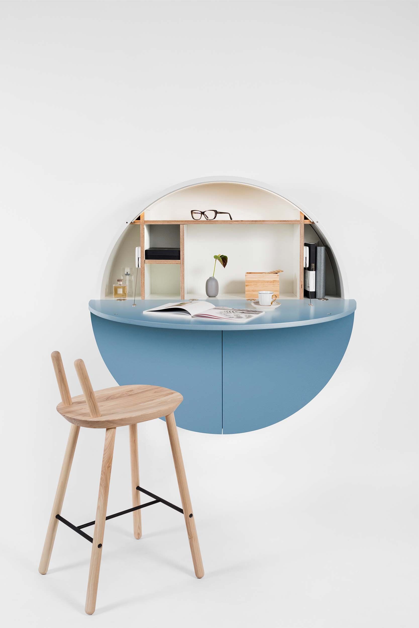 A sleek, round wall-mounted cabinet that transforms into a workspace, dressing table, or bar, featuring adjustable height and customizable shelving.