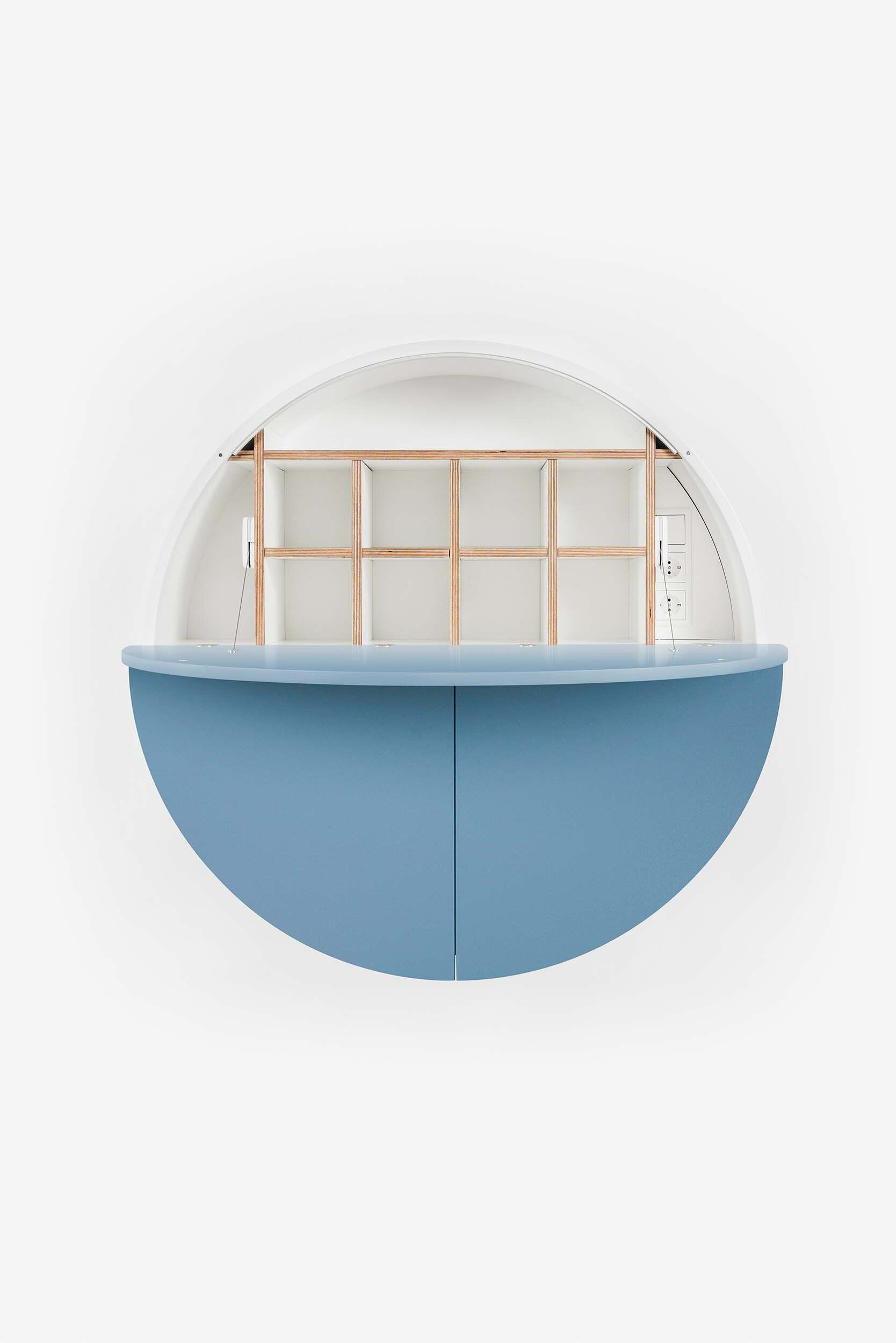 A sleek, round wall-mounted cabinet that transforms into a workspace, dressing table, or bar, featuring adjustable height and customizable shelving.