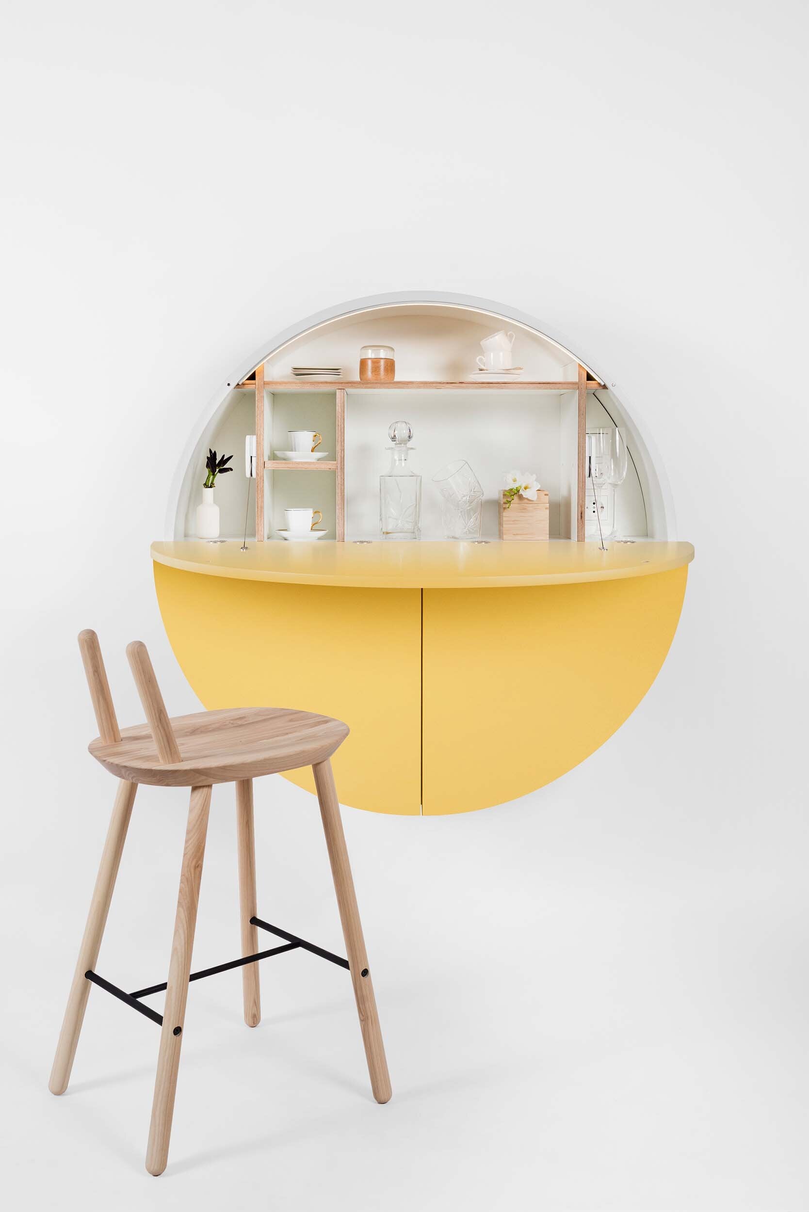 A sleek, round wall-mounted cabinet that transforms into a workspace, dressing table, or bar, featuring adjustable height and customizable shelving.