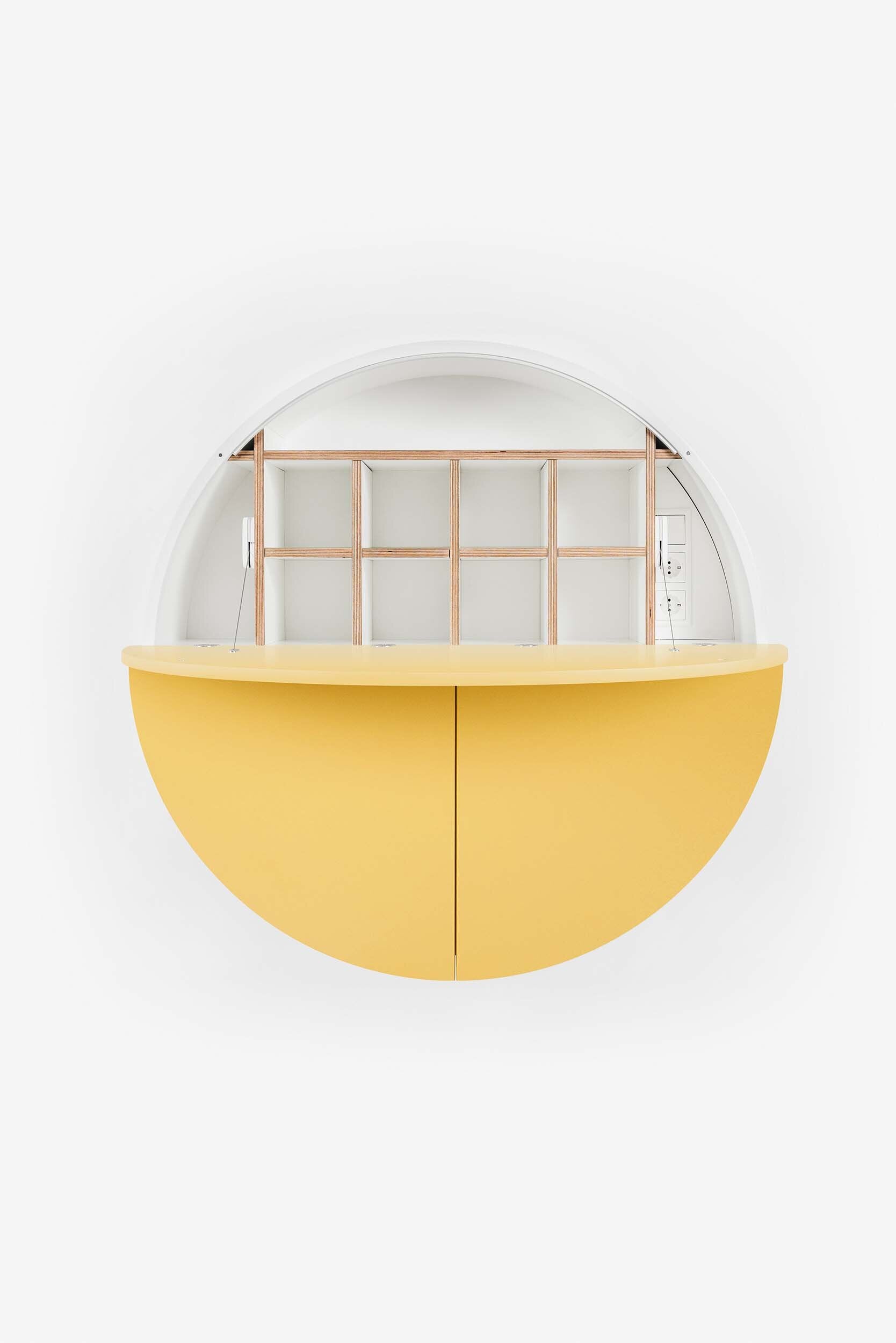 A sleek, round wall-mounted cabinet that transforms into a workspace, dressing table, or bar, featuring adjustable height and customizable shelving.