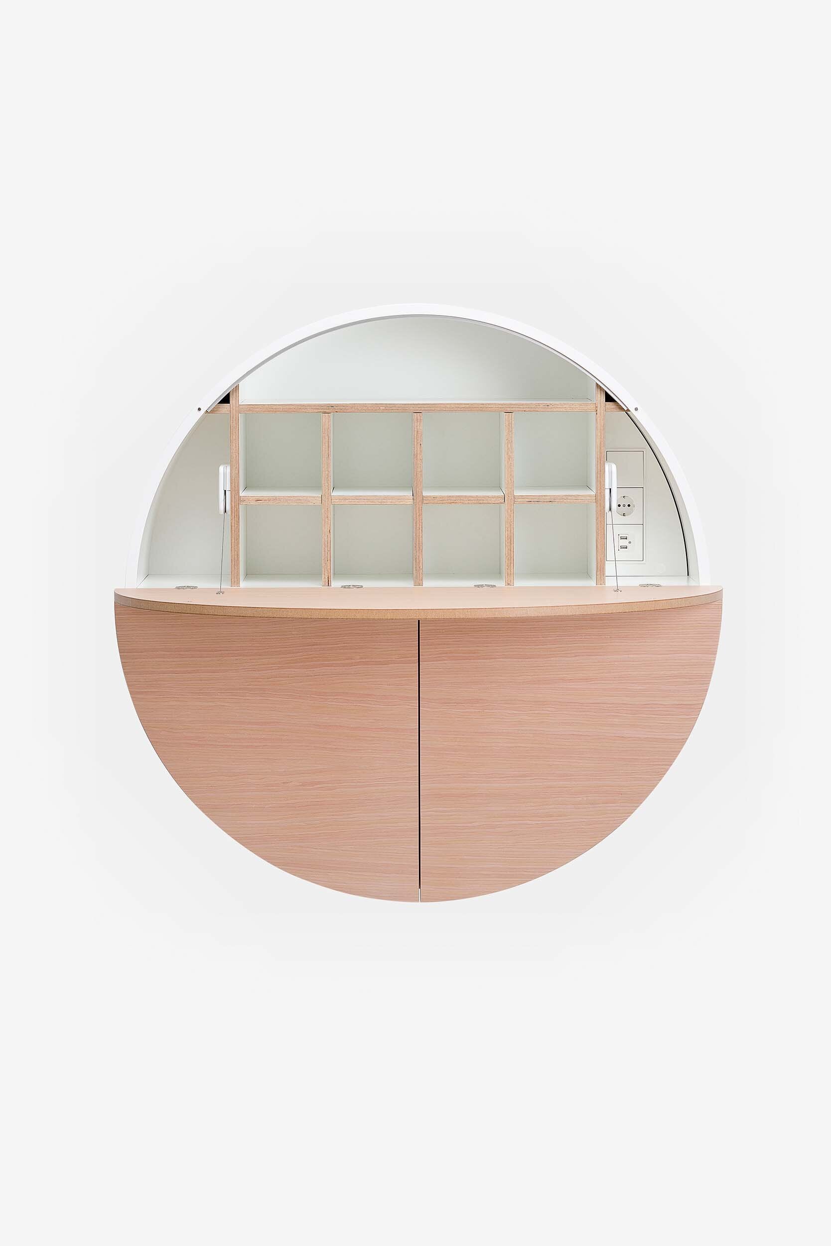 A sleek, round wall-mounted cabinet that transforms into a workspace, dressing table, or bar, featuring adjustable height and customizable shelving.