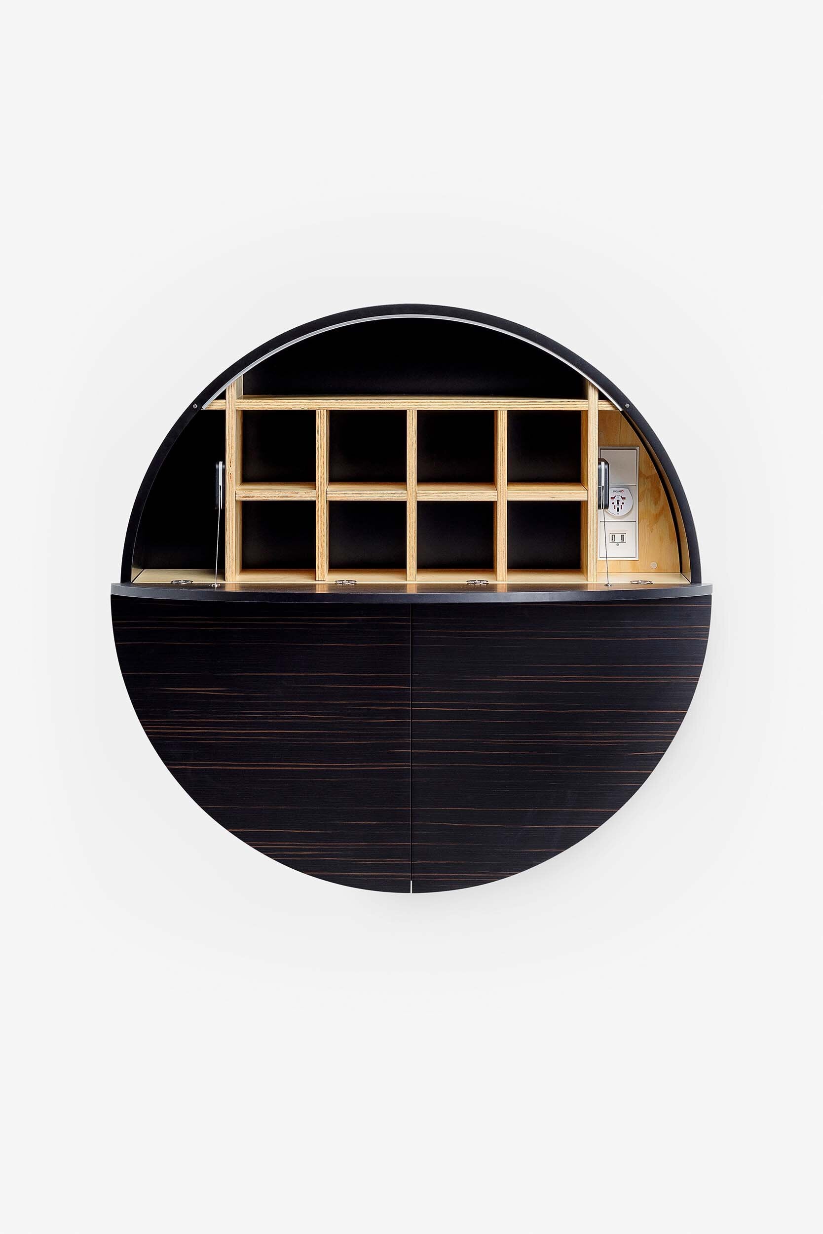 A sleek, round wall-mounted cabinet that transforms into a workspace, dressing table, or bar, featuring adjustable height and customizable shelving.