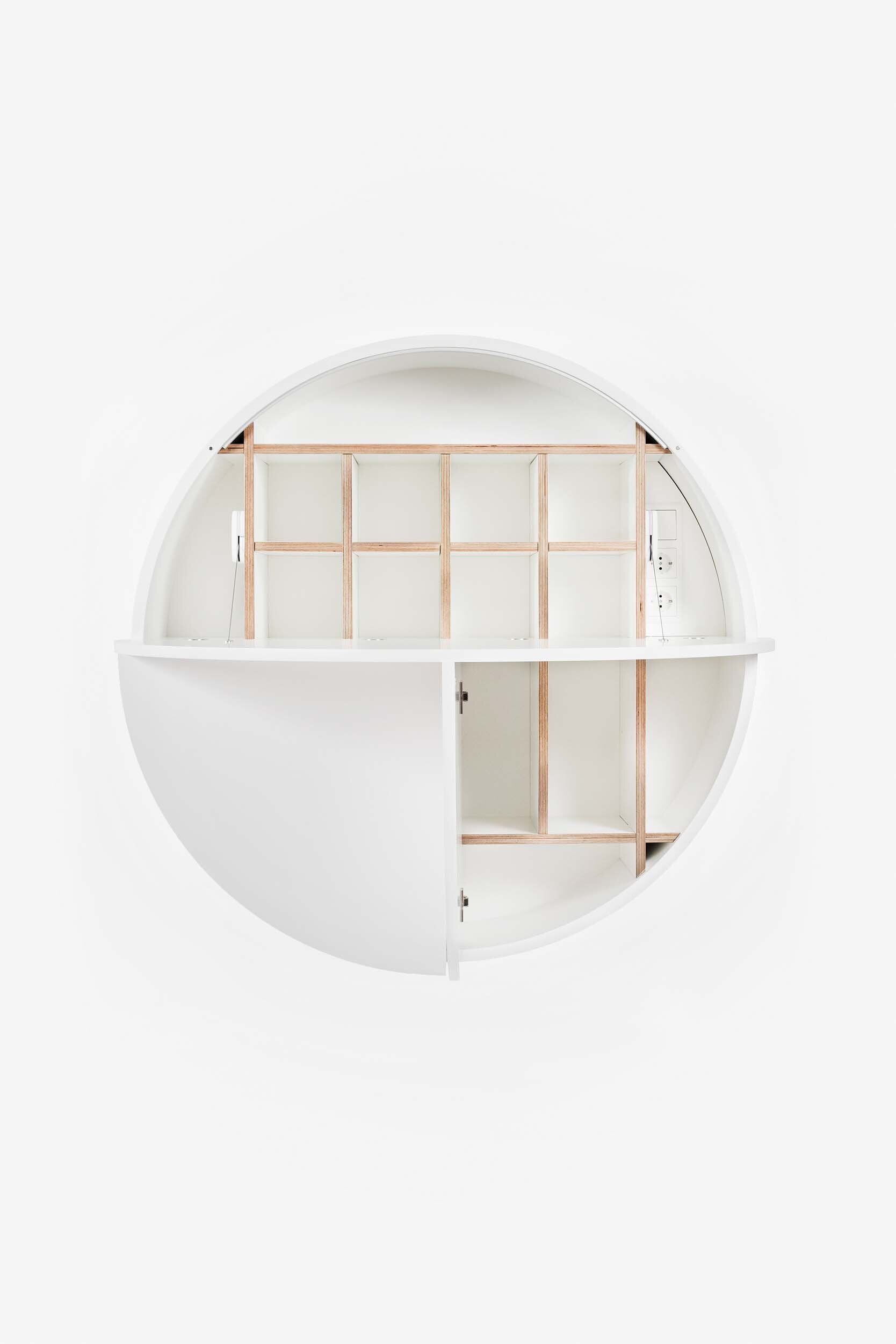 A sleek, round wall-mounted cabinet that transforms into a workspace, dressing table, or bar, featuring adjustable height and customizable shelving.