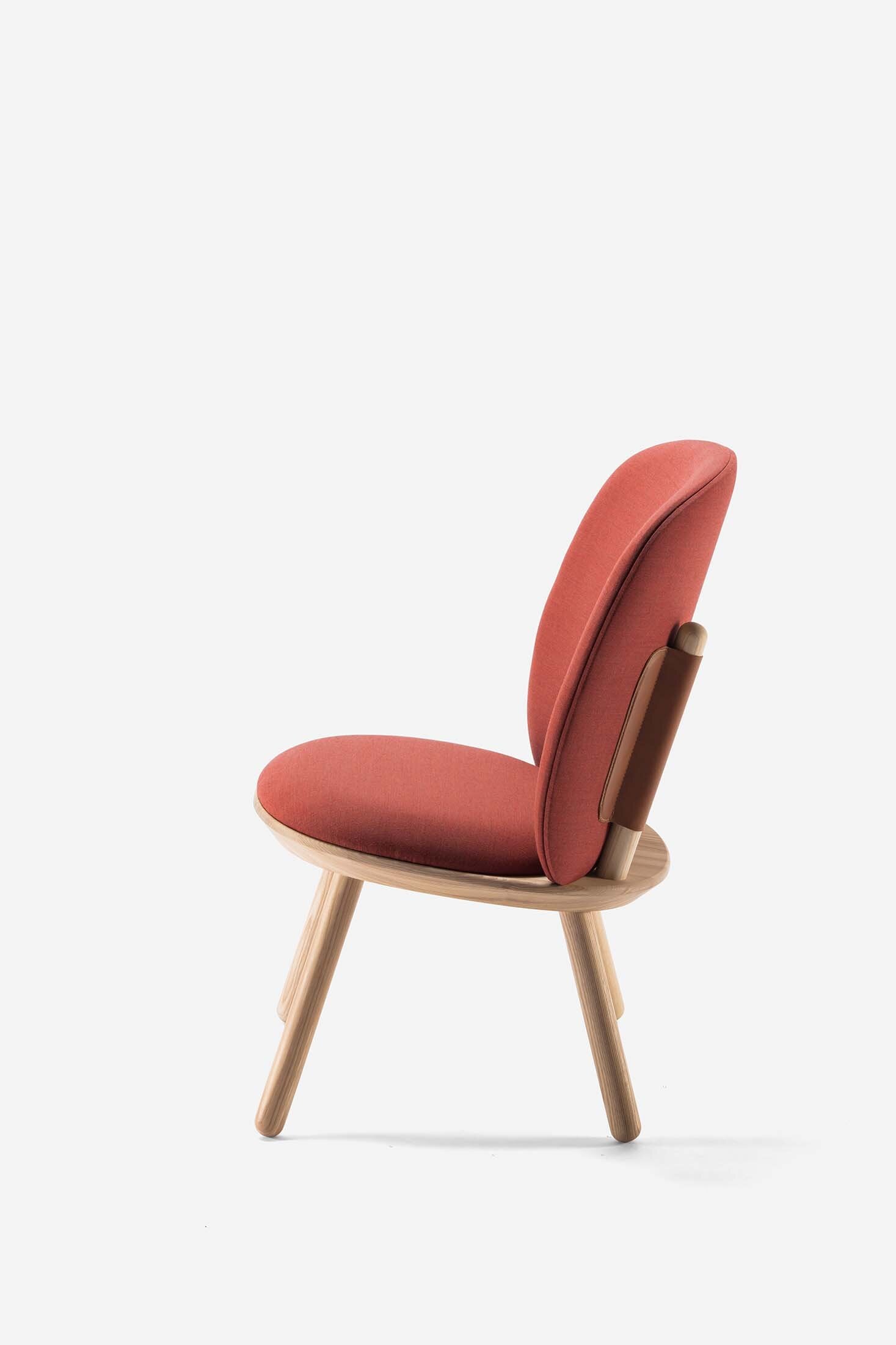 Naïve Low Chair featuring a large leather strap, wooden body, and textile upholstery, designed for comfort and style.