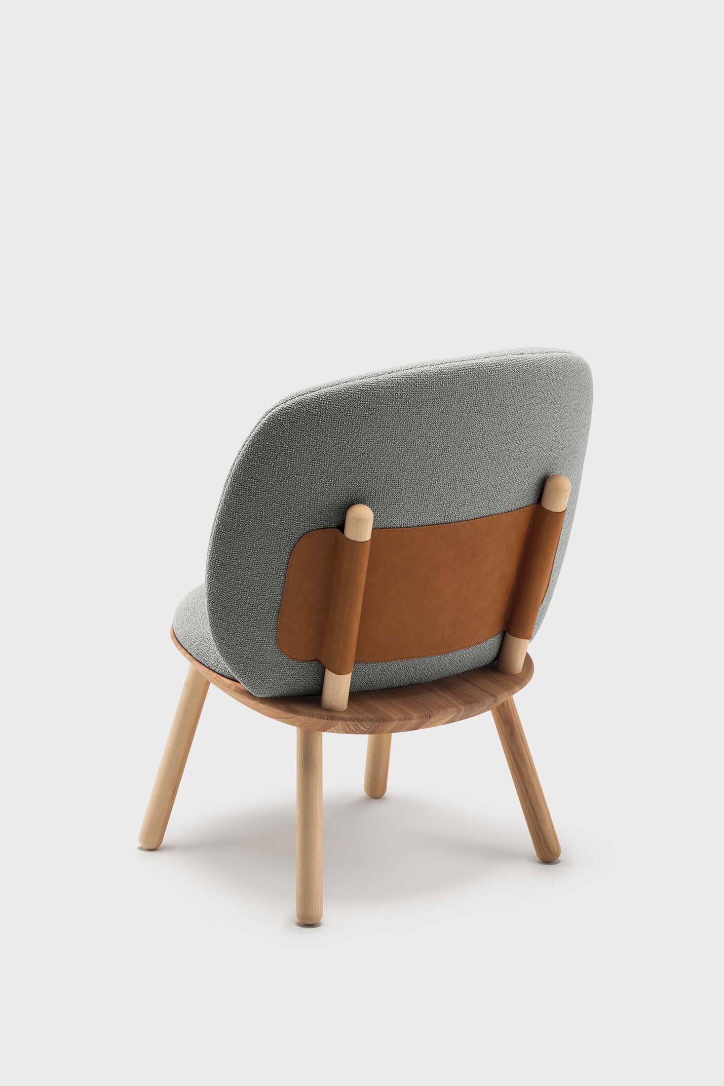 Naïve Low Chair featuring a large leather strap, wooden body, and textile upholstery, designed for comfort and style.