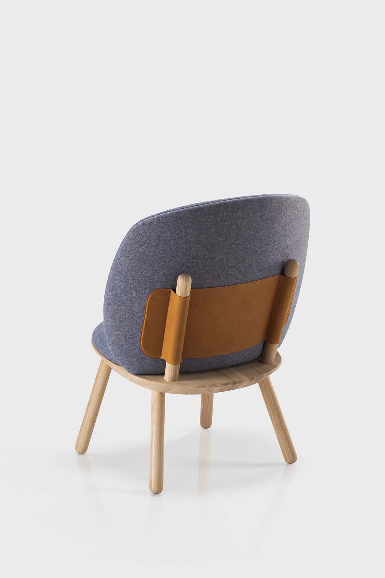 Naïve Low Chair featuring a large leather strap, wooden body, and textile upholstery, designed for comfort and style.