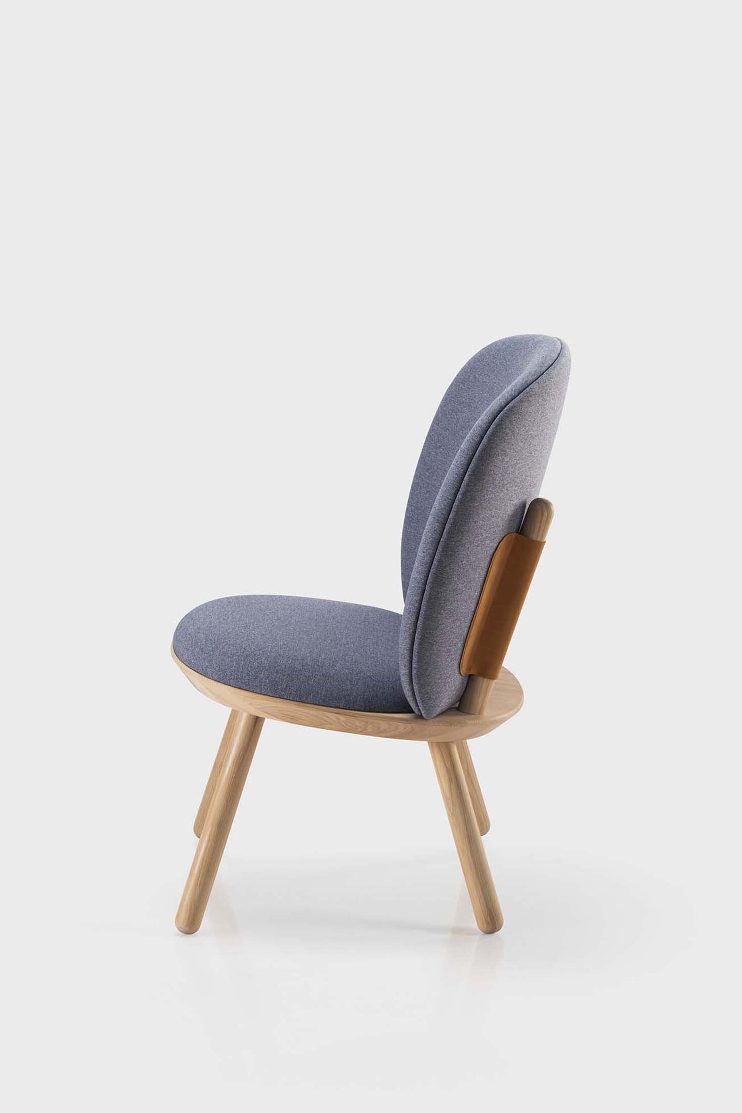 Naïve Low Chair featuring a large leather strap, wooden body, and textile upholstery, designed for comfort and style.