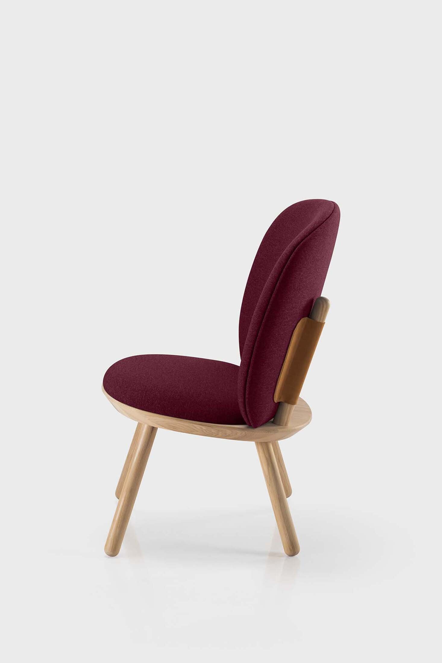 Naïve Low Chair featuring a large leather strap, wooden body, and textile upholstery, designed for comfort and style.