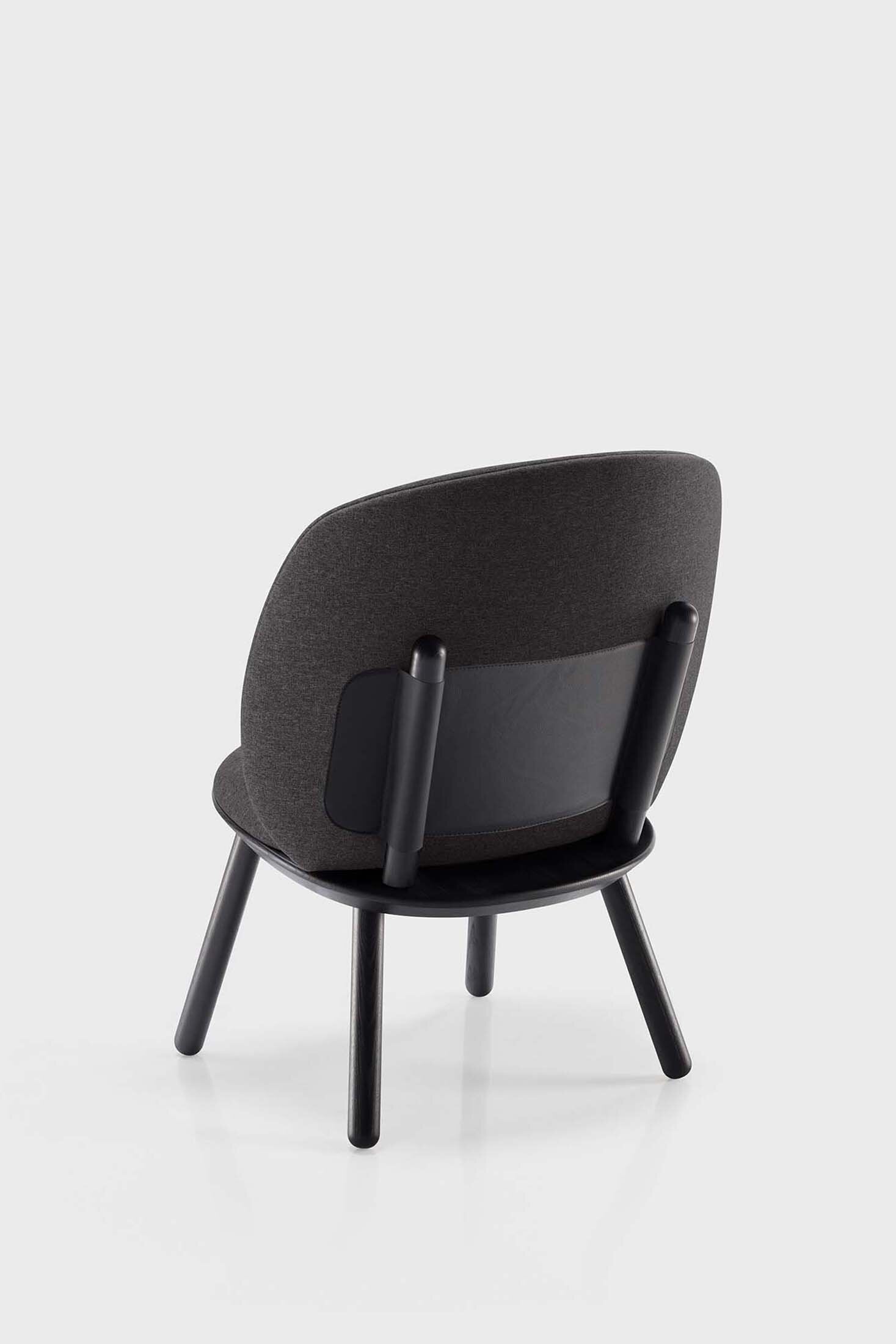 Naïve Low Chair featuring a large leather strap, wooden body, and textile upholstery, designed for comfort and style.