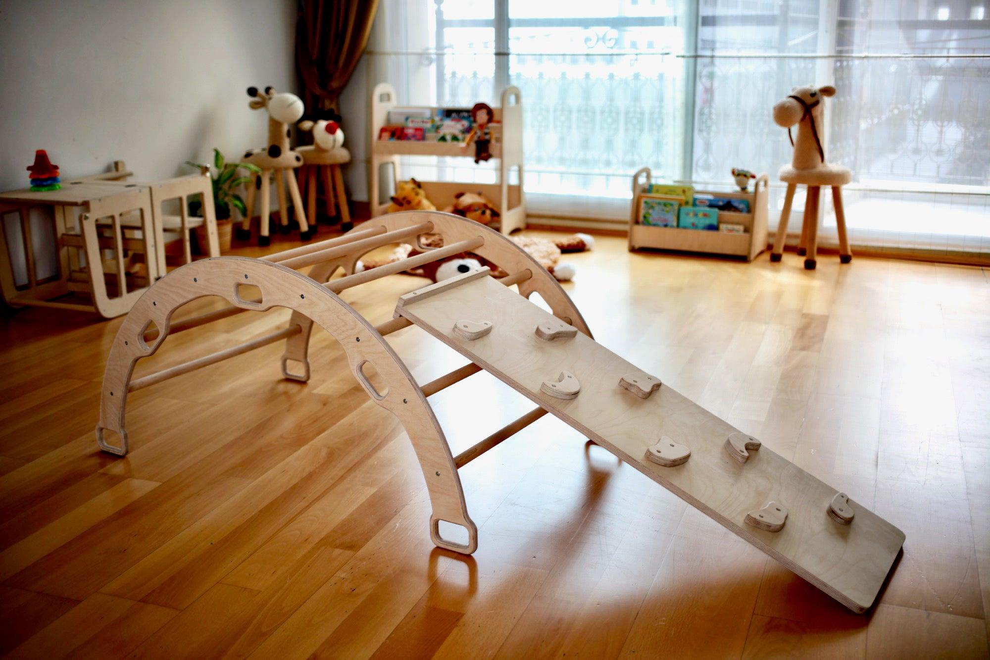 A child climbing on a reversible rockwall while another child prepares to slide down the smooth ramp, showcasing the dual functionality of the play system.