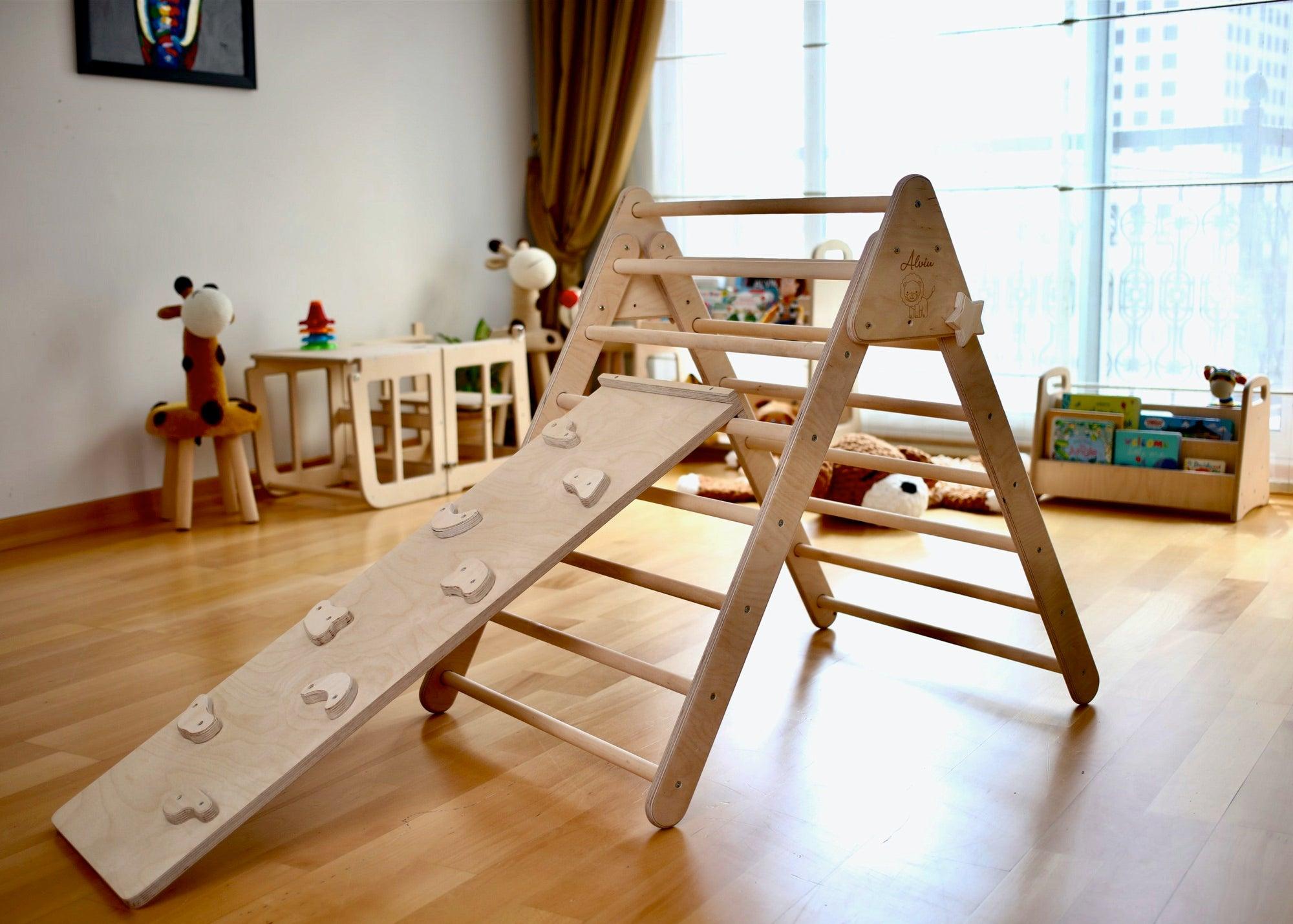 A child climbing on a reversible rockwall while another child prepares to slide down the smooth ramp, showcasing the dual functionality of the play system.