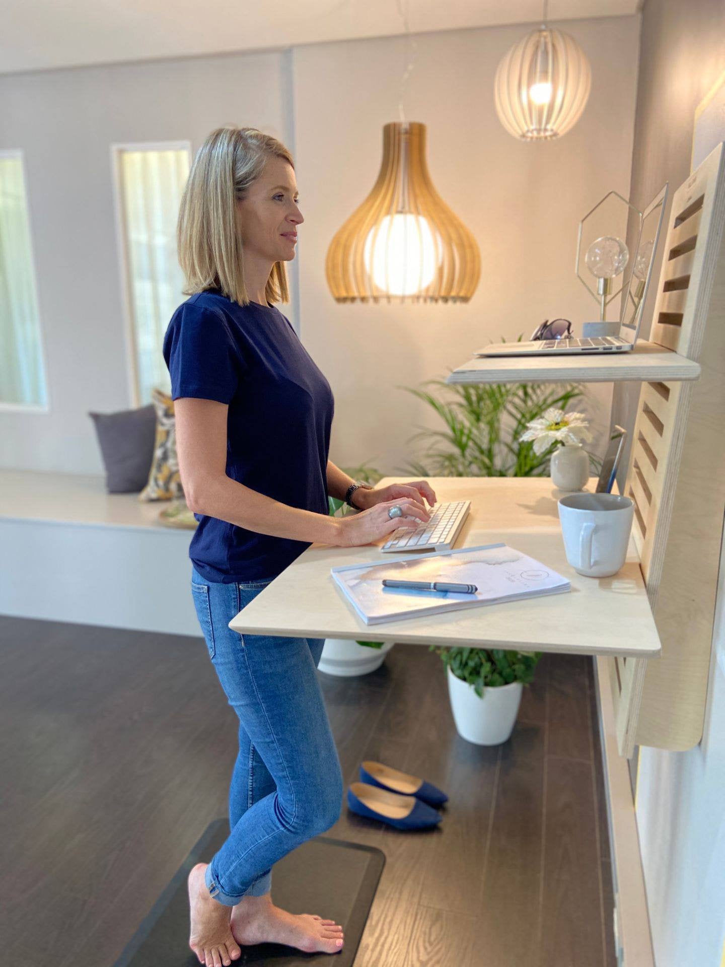 WallStand adjustable wall-mounted standing desk with two shelves, showcasing a sleek design and premium Baltic Birch plywood material.