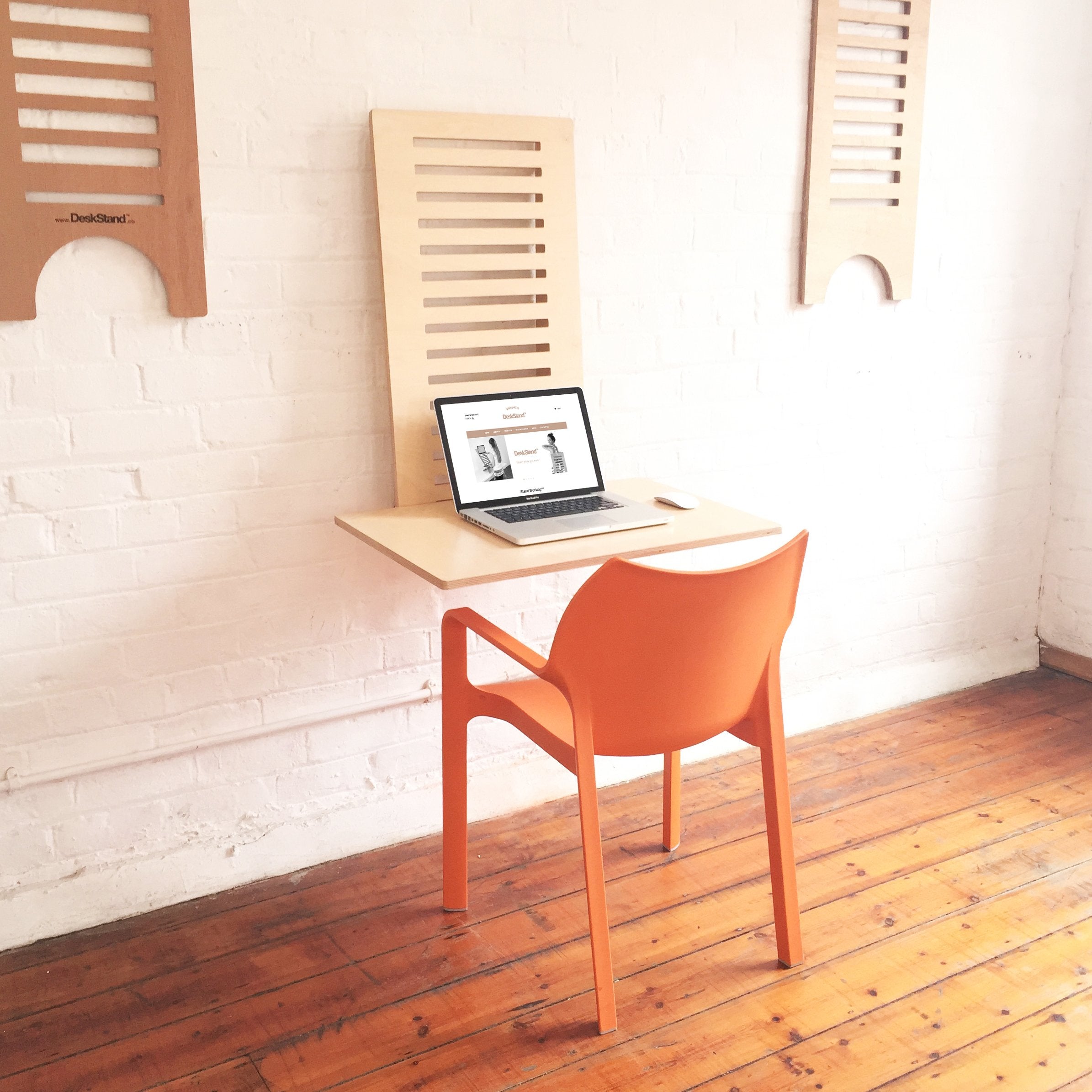 WallStand adjustable wall-mounted standing desk with two shelves, showcasing a sleek design and premium Baltic Birch plywood material.