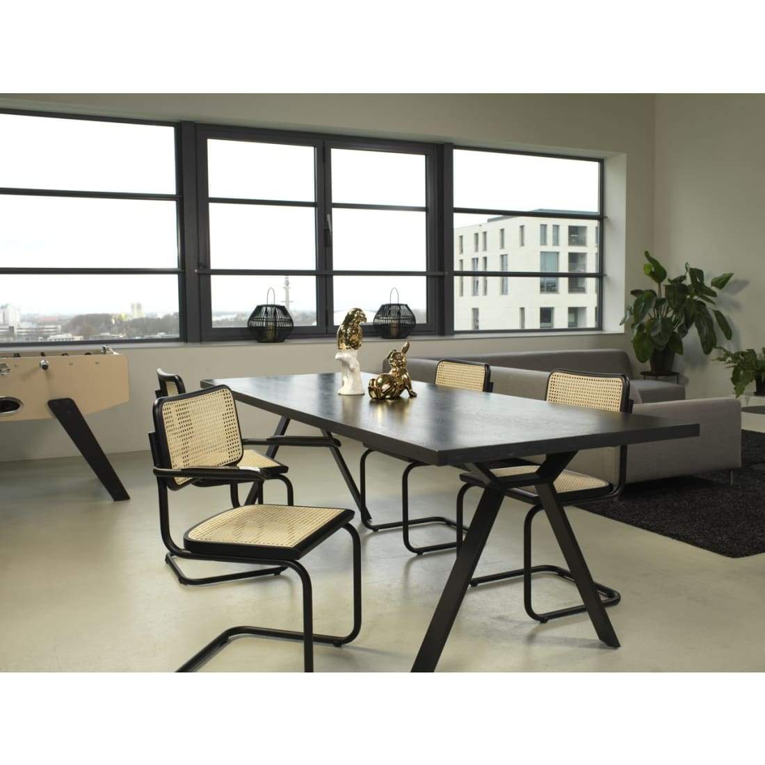 Workliving Bas Eetkamerstoel featuring a sleek black rattan design with armrests, perfect for dining rooms.