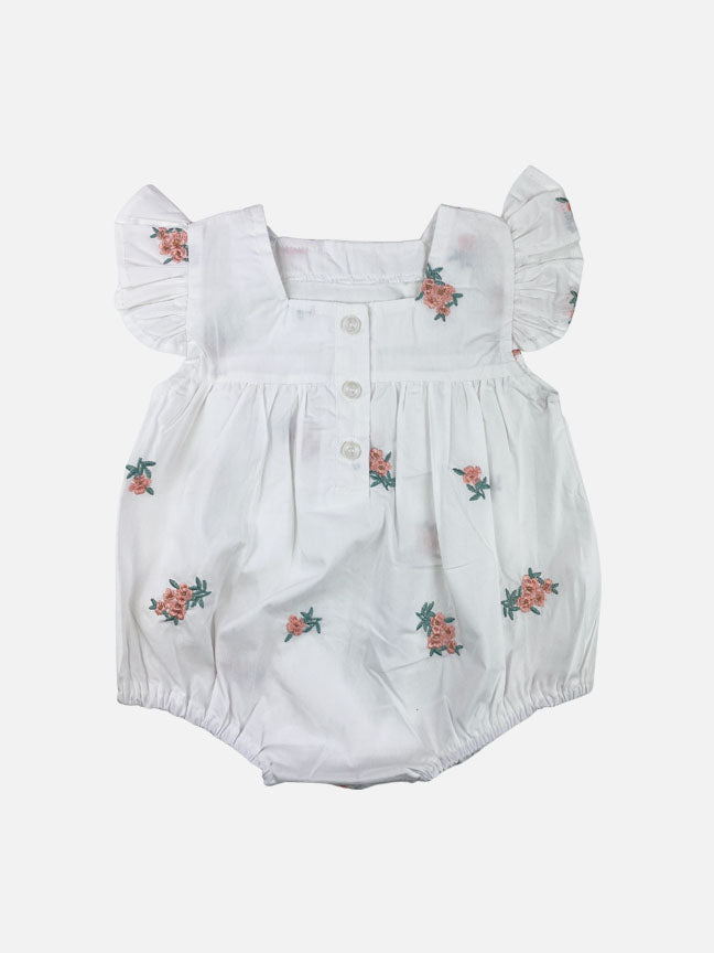 Adeline 2 pc onesie set featuring white cotton fabric with pink and green floral embroidery, ruffle sleeves, and a matching tie bonnet.