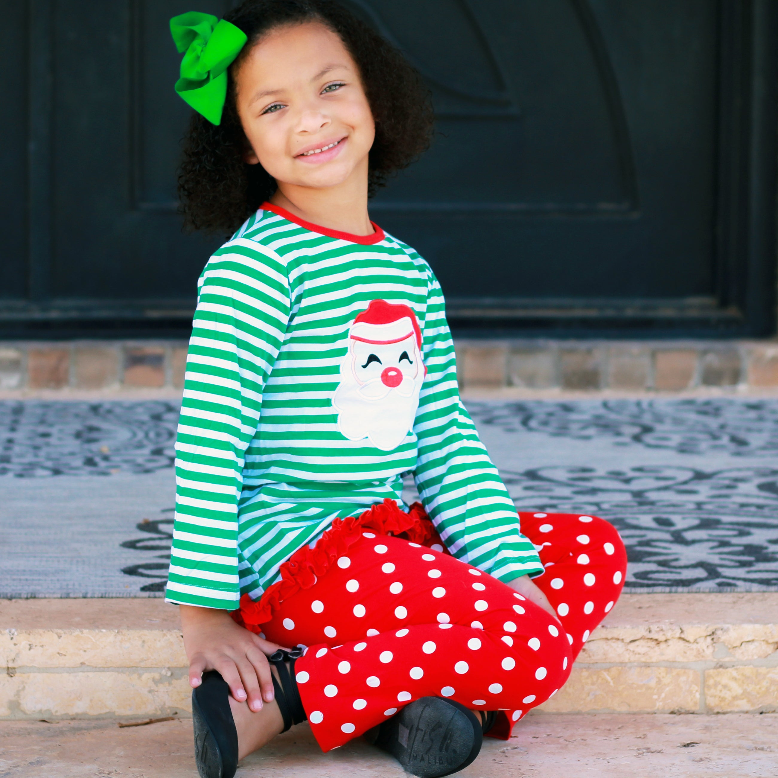 A festive girls' outfit featuring a Santa tunic top with ruffle trim and red polka dot pants, perfect for holiday celebrations.