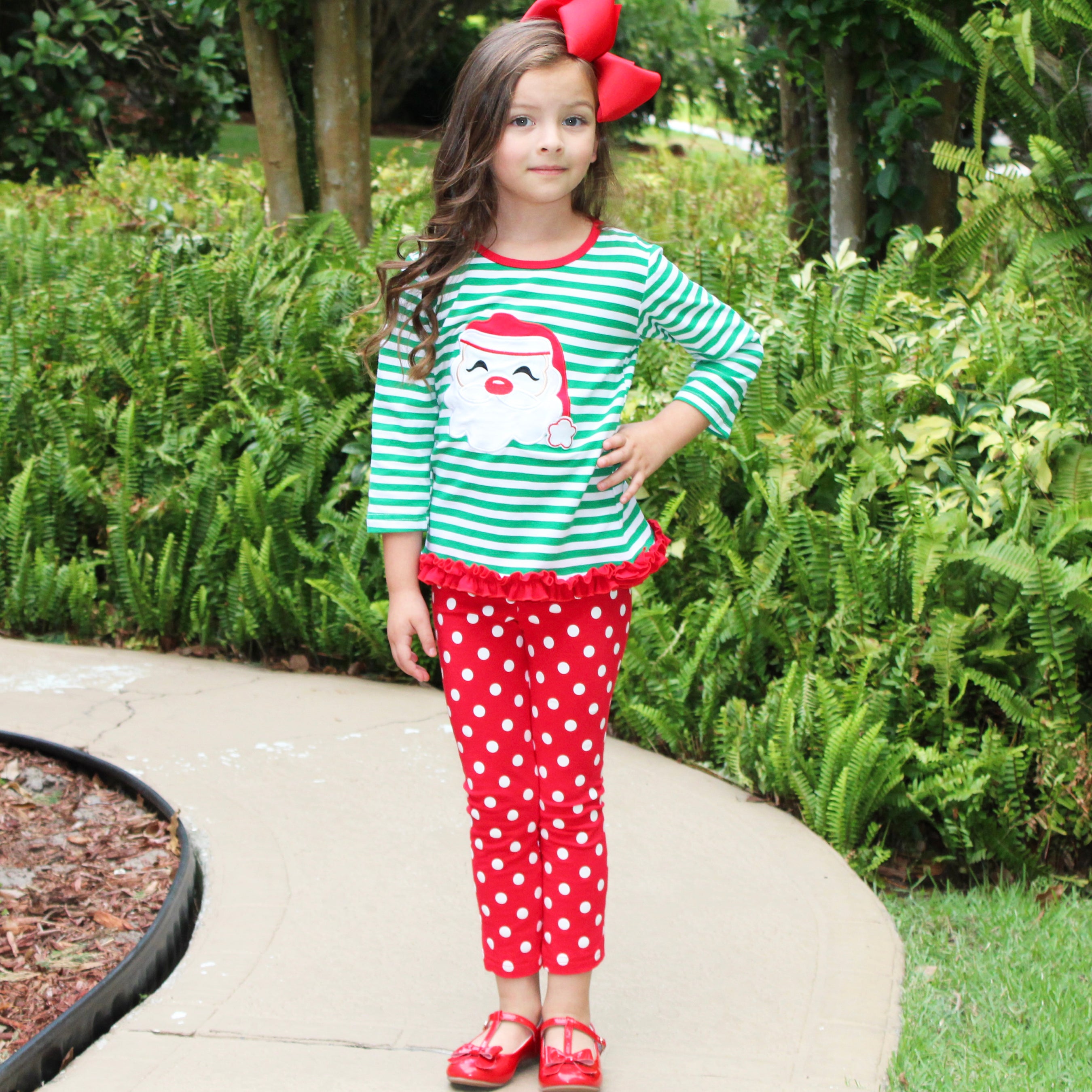 A festive girls' outfit featuring a Santa tunic top with ruffle trim and red polka dot pants, perfect for holiday celebrations.