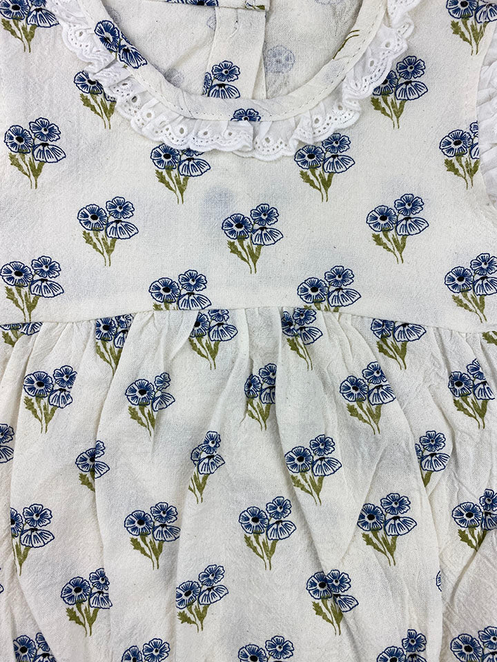 A blue floral Belle Onesie made of soft cotton, featuring eyelet lace details on the collar and sleeves, perfect for babies.