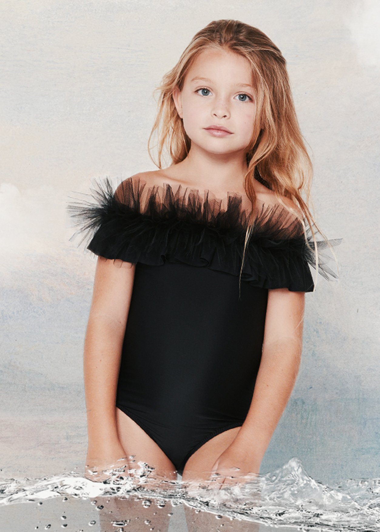 Black draped swimsuit for girls featuring tulle accents, perfect for beach outings.