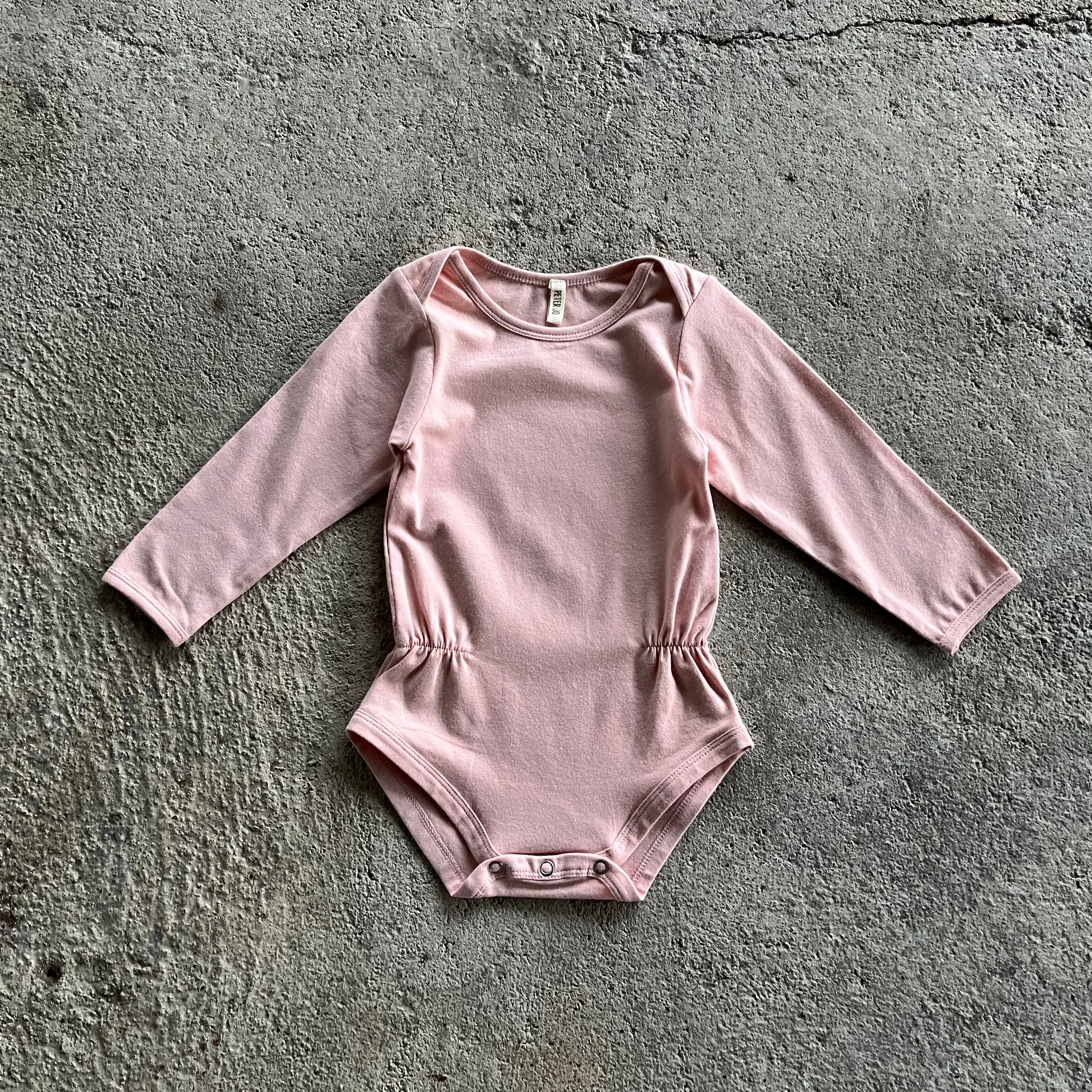 A soft pink body for babies and toddlers with elasticised waist and snap closures, made from organic cotton and elastane.