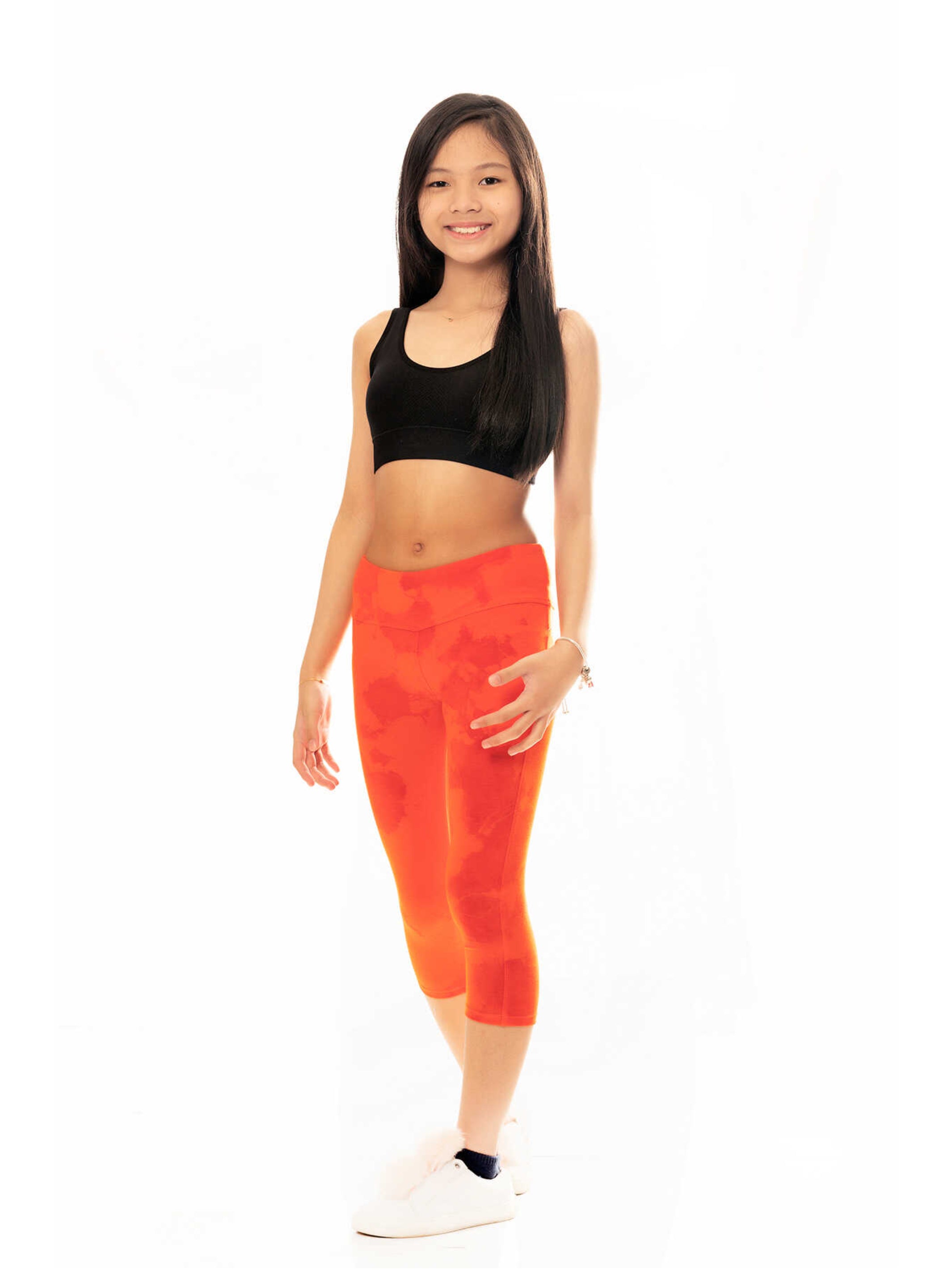 Bright orange tie dye capri leggings made from soft cotton knit with an elastic waistband, perfect for summer wear.