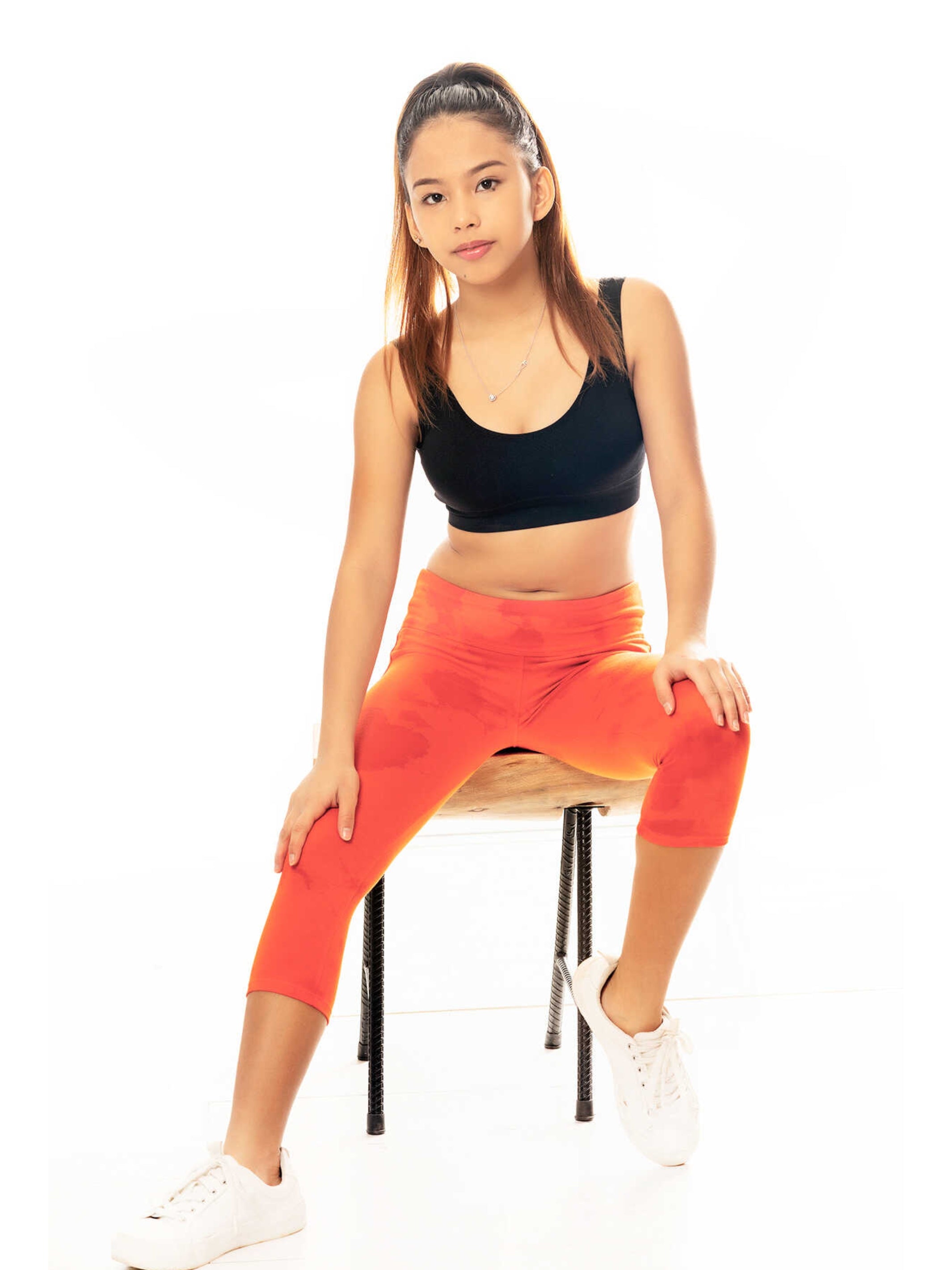 Bright orange tie dye capri leggings made from soft cotton knit with an elastic waistband, perfect for summer wear.