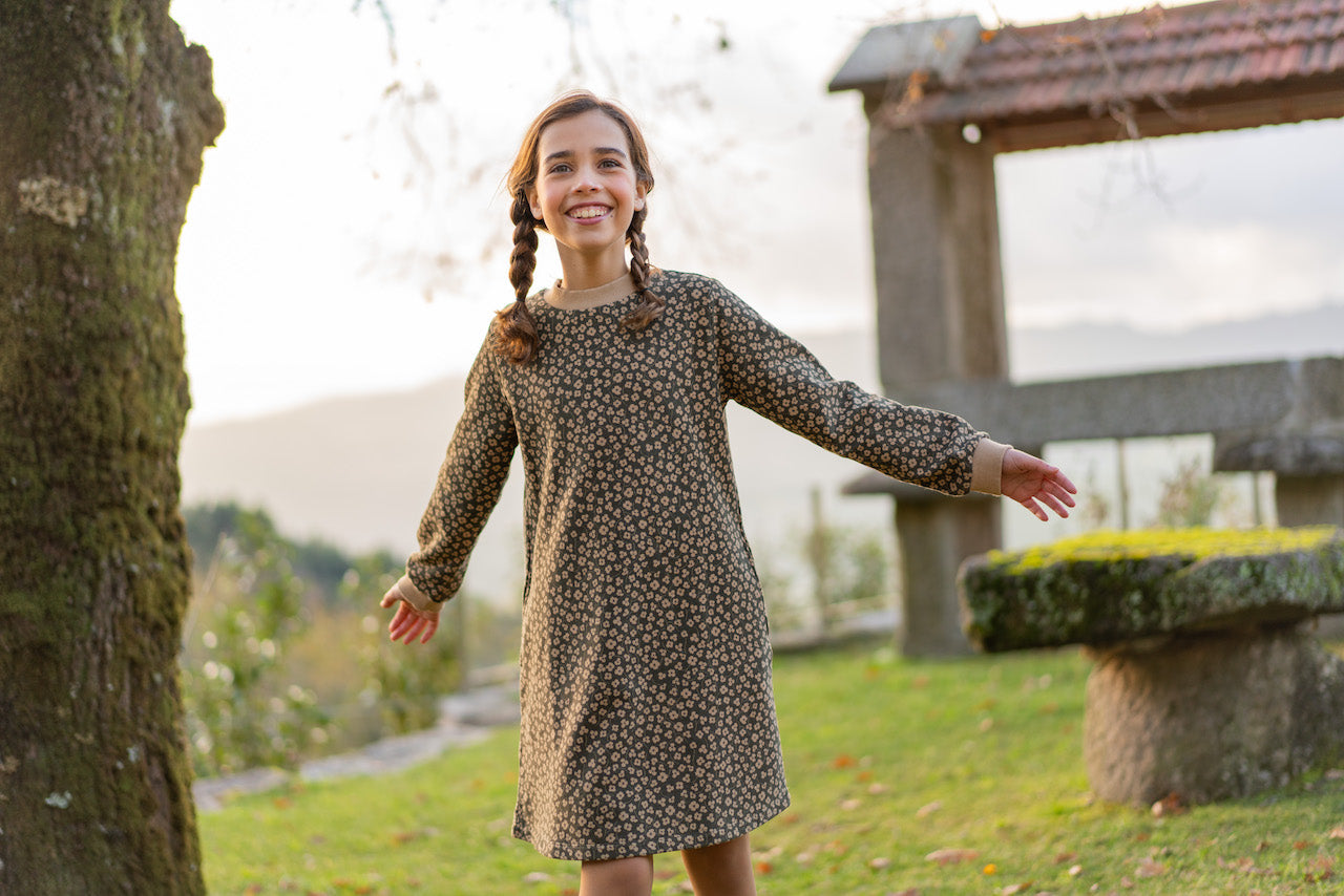 A stylish long sleeve dress featuring a khaki floral print, made from organic cotton fleece with ribbed cuffs and side pockets.