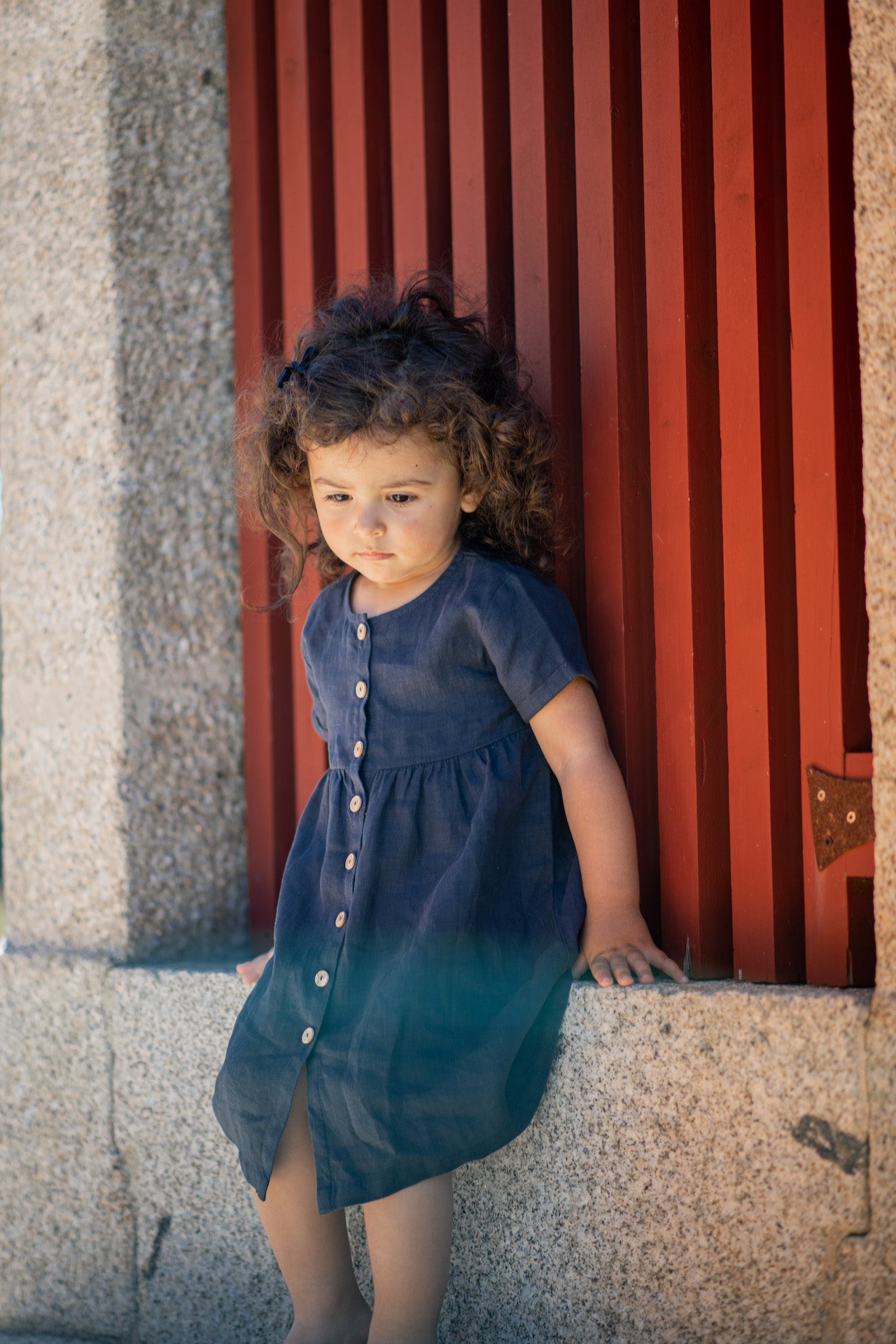 A stylish terracotta dress made of 100% linen, featuring short sleeves with rolled cuffs and olive wood button closure.