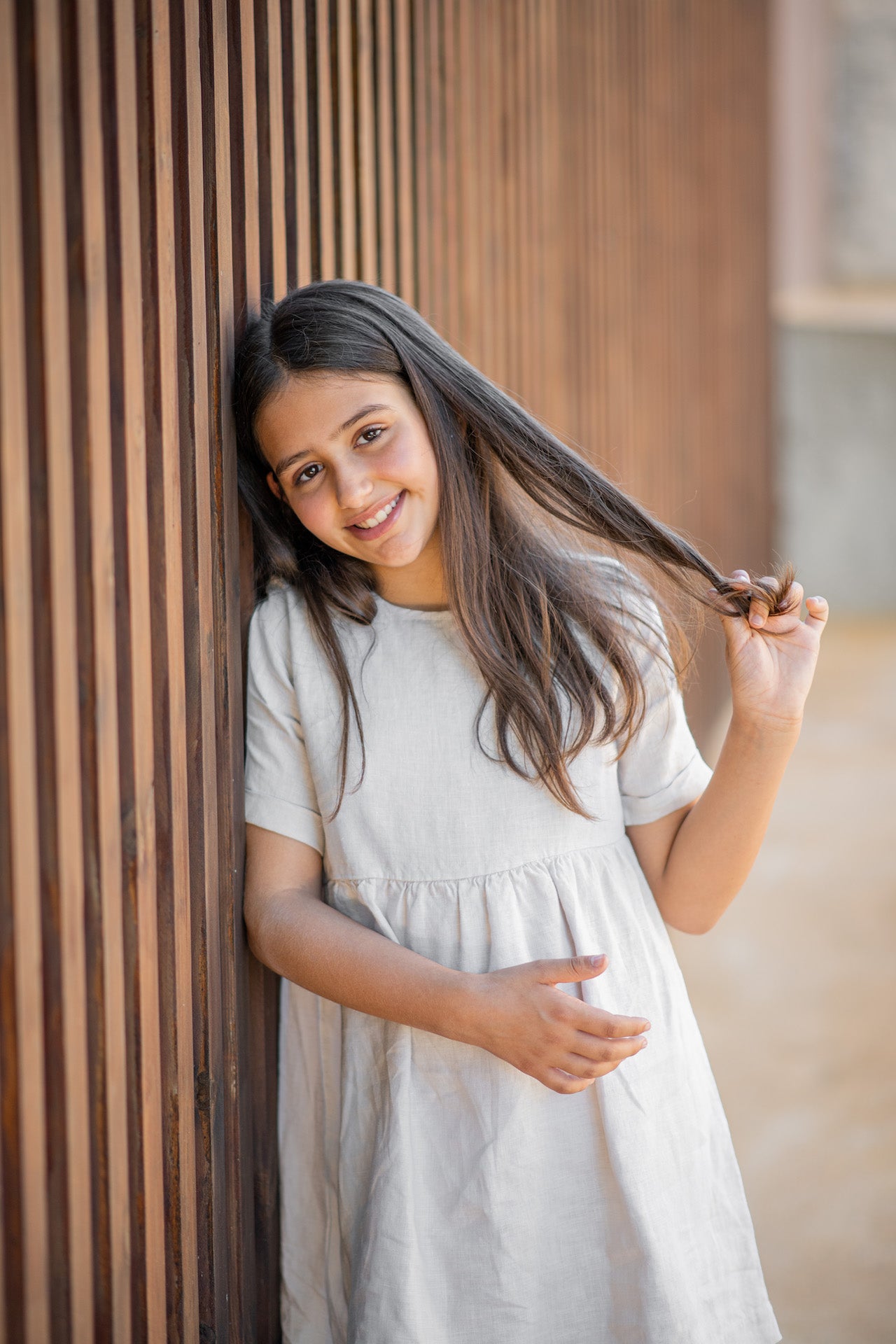 A modern casual dress in cream color made of soft linen, featuring rolled cuff sleeves and an olive wood button closure at the back.