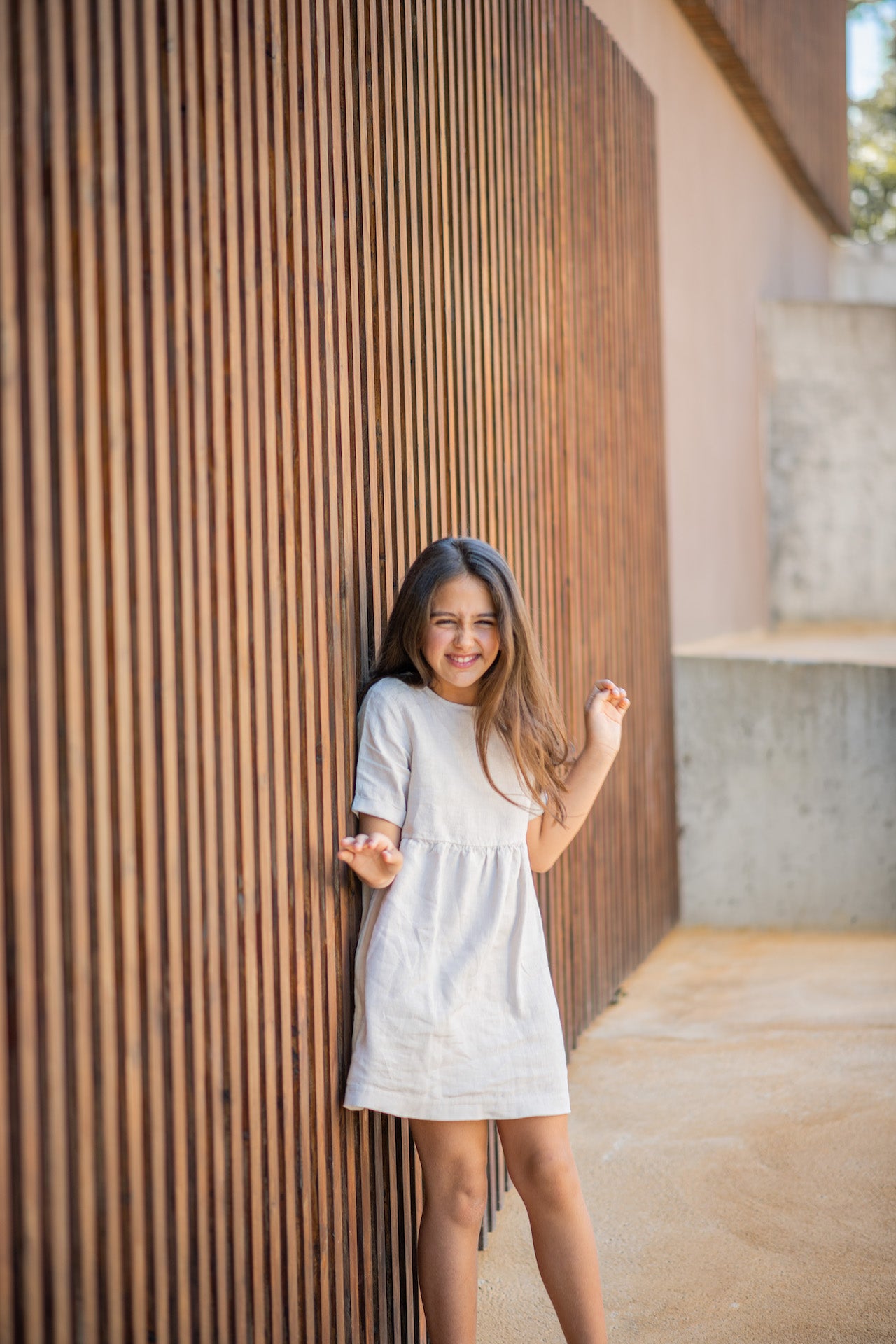 A modern casual dress in cream color made of soft linen, featuring rolled cuff sleeves and an olive wood button closure at the back.