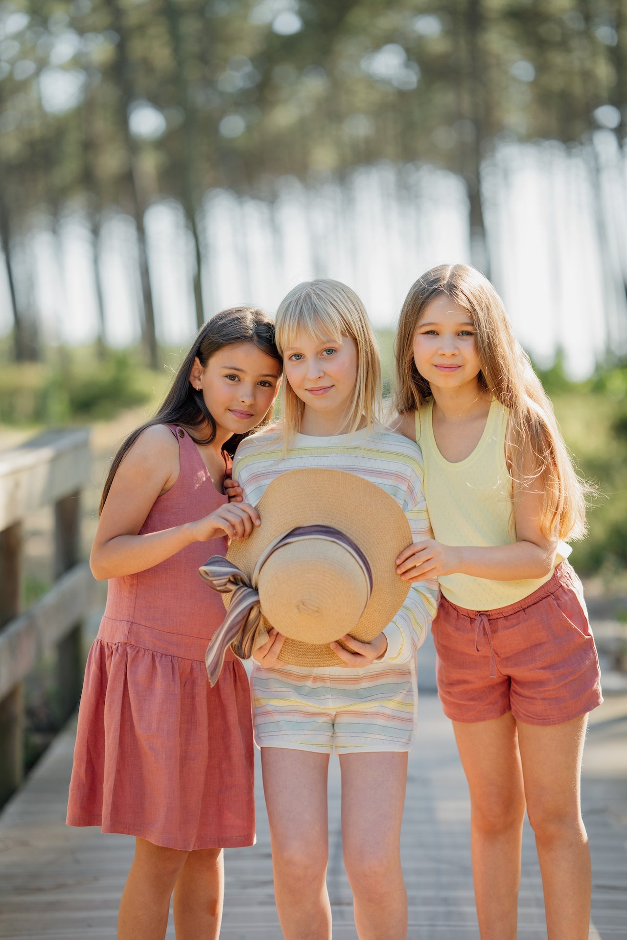 Dungaree Celeste dress in soft natural linen, featuring adjustable straps and a side zip, available in Rose, Blue Celeste, and Sienna Cream.