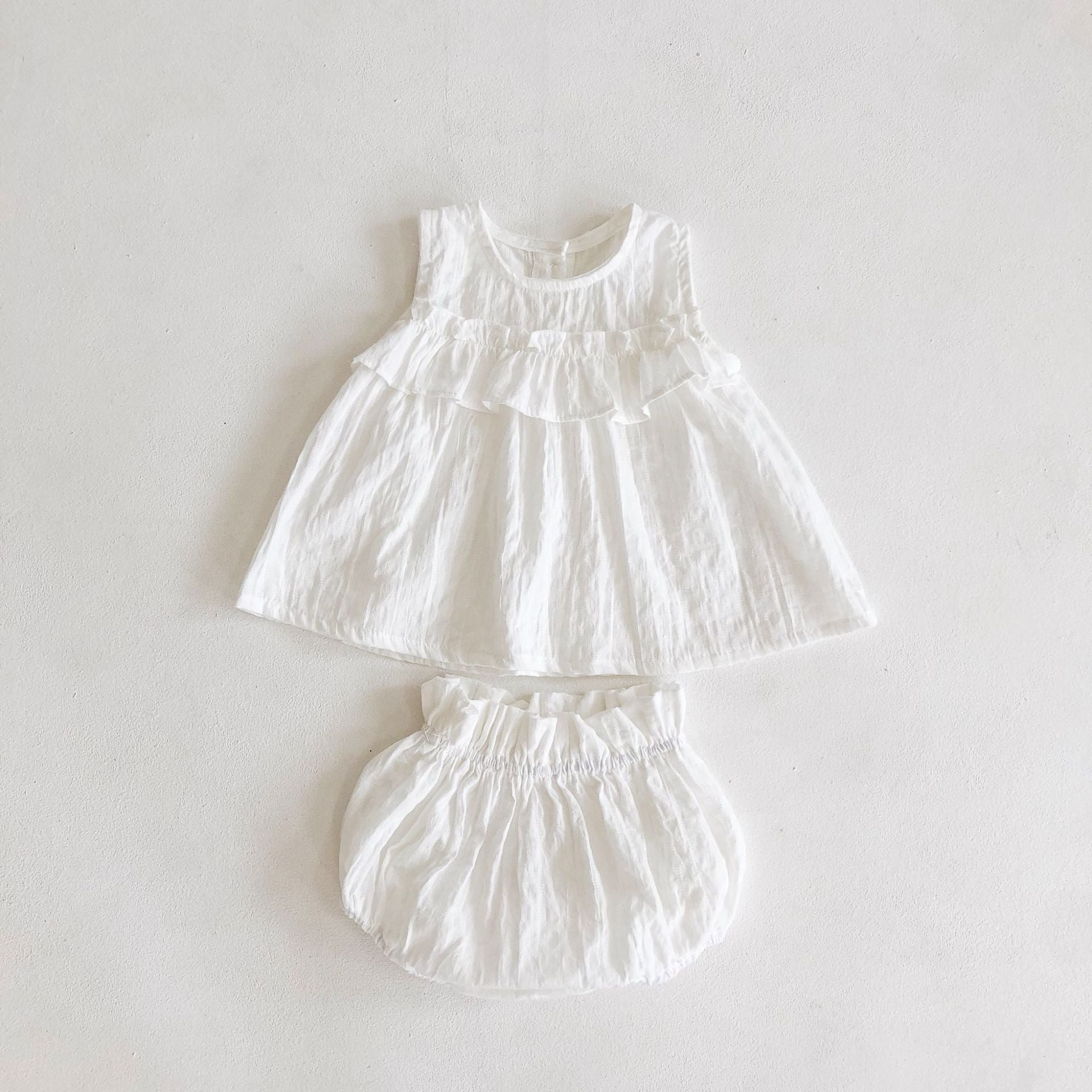 Eloise 2 pc set featuring a pale peach tank top with ruffles and matching bloomer shorts, made of textured cotton fabric.