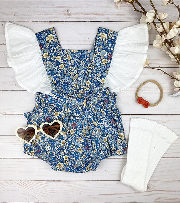 Everly Flutter Bow Onesie in blue floral print with ruffled sleeves and a large bow at the back.