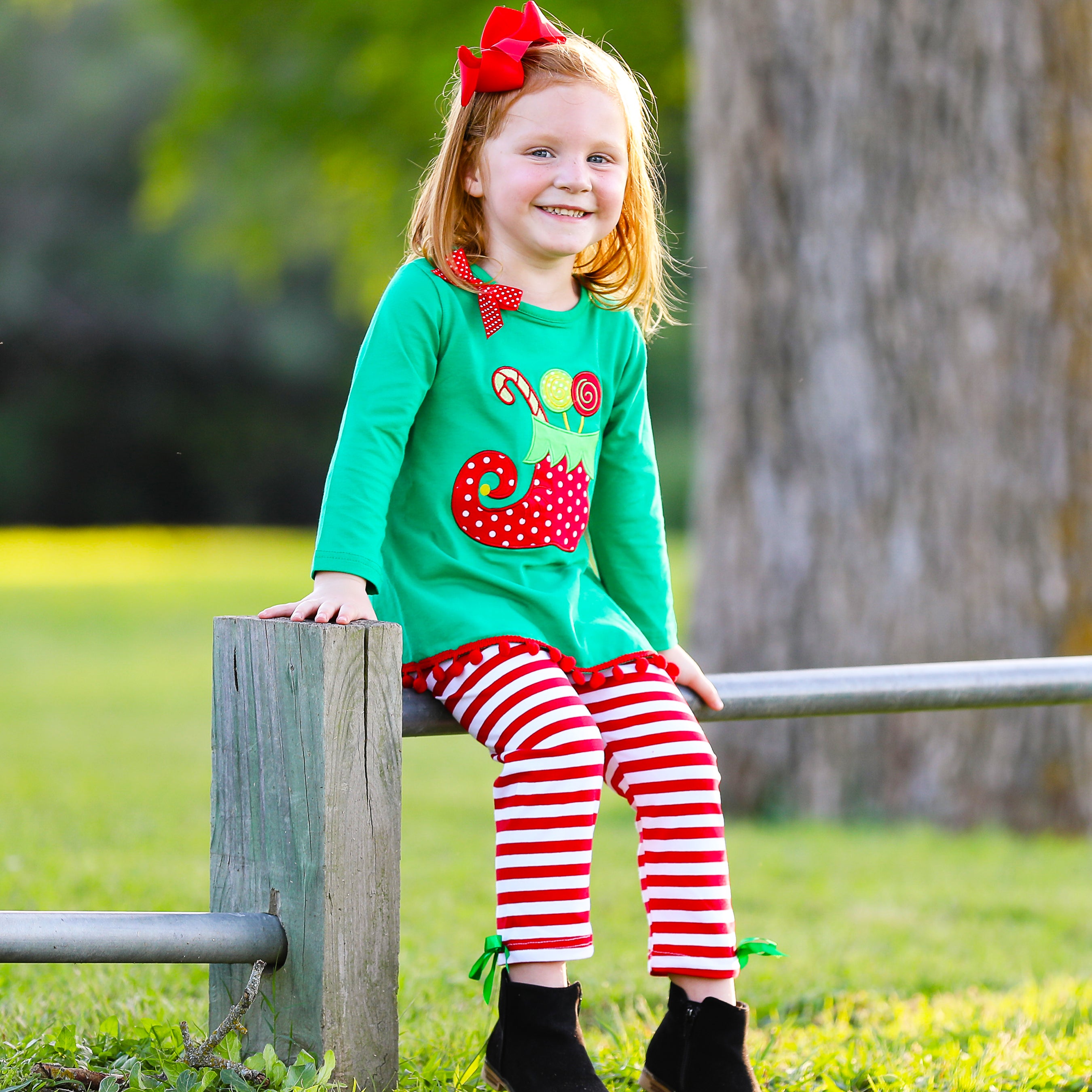 A festive girls outfit featuring an Elf Stocking top with pom pom trim and red & white striped pants, perfect for Christmas celebrations.