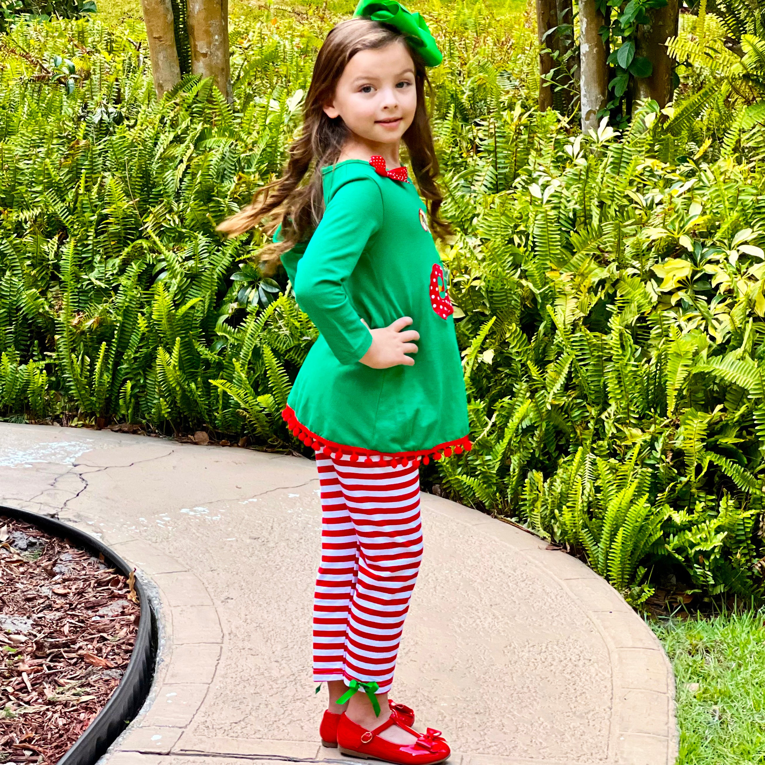 A festive girls outfit featuring an Elf Stocking top with pom pom trim and red & white striped pants, perfect for Christmas celebrations.