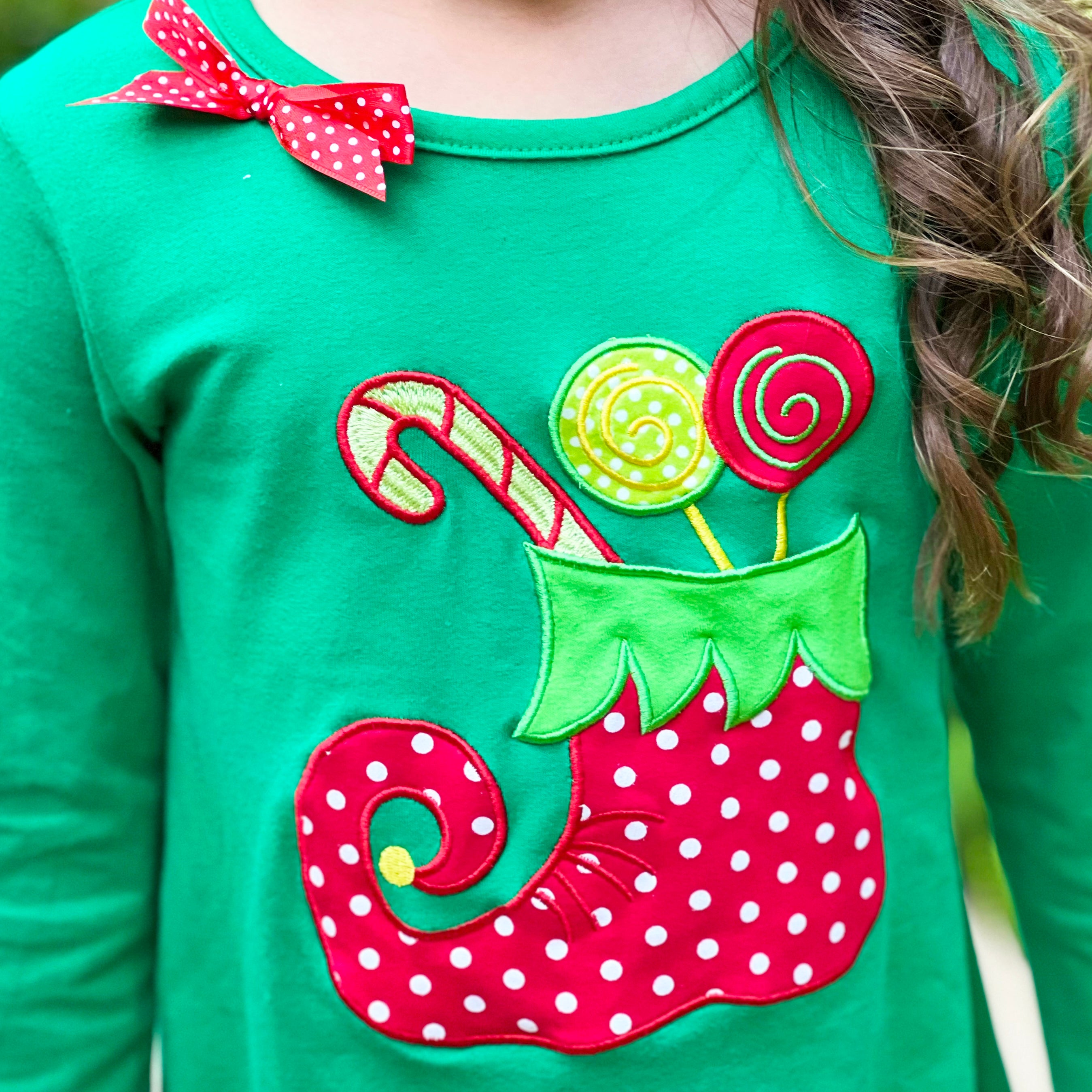 A festive girls outfit featuring an Elf Stocking top with pom pom trim and red & white striped pants, perfect for Christmas celebrations.