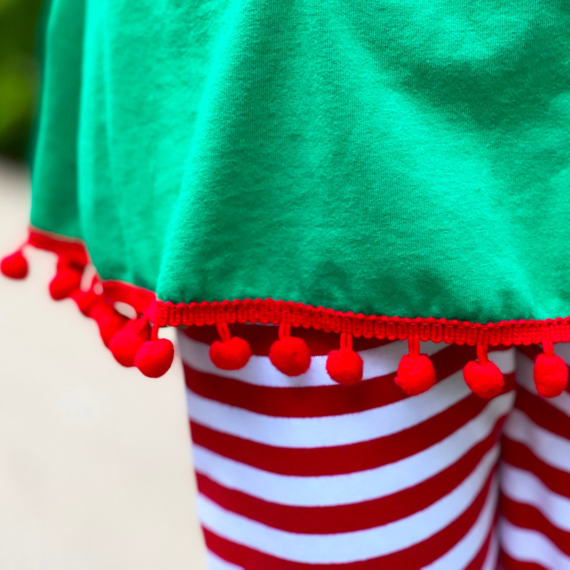 A festive girls outfit featuring an Elf Stocking top with pom pom trim and red & white striped pants, perfect for Christmas celebrations.