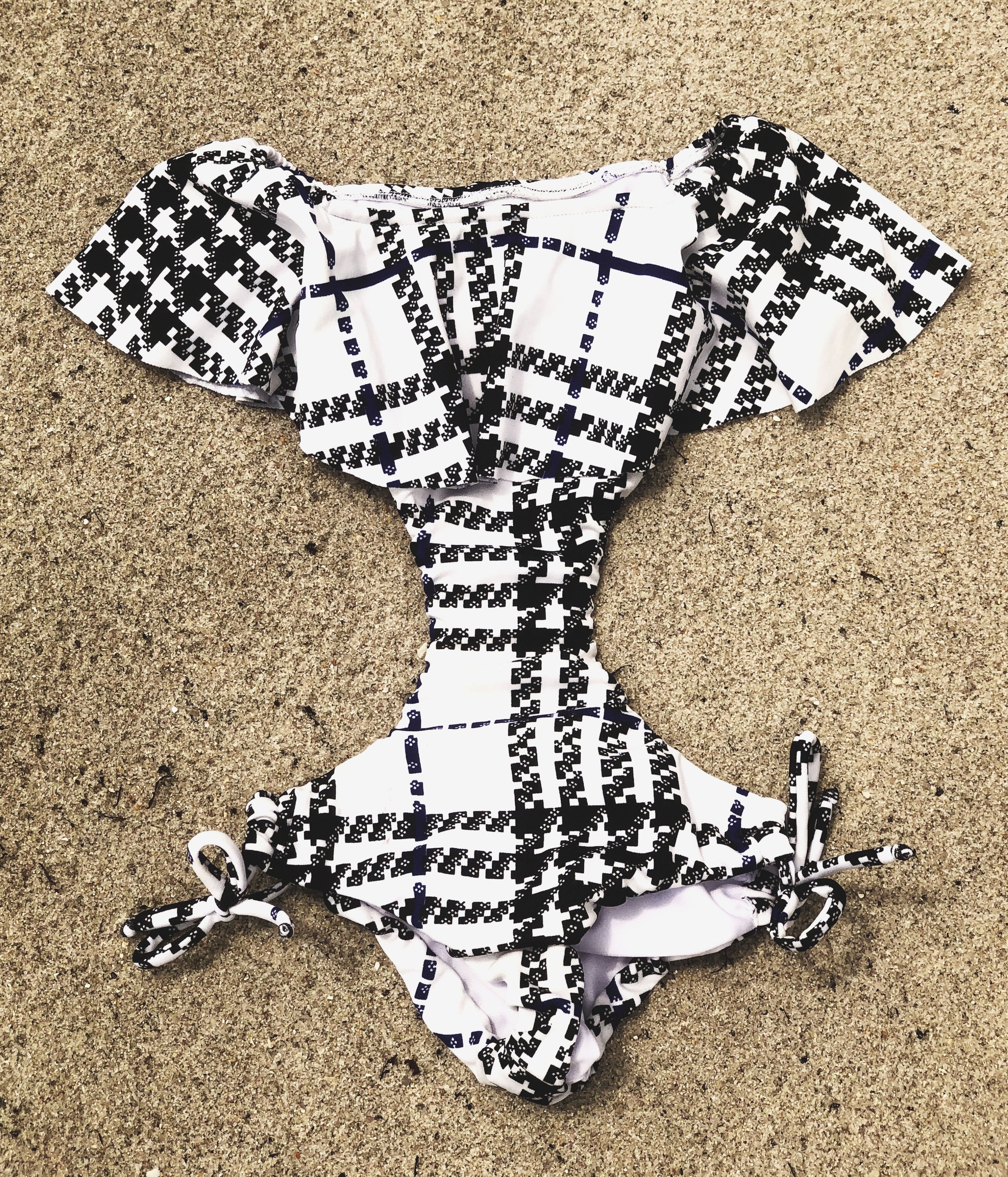 I Plaid You Trikini for kids featuring a stylish black and white design with off-shoulder style and adjustable side ribbons.