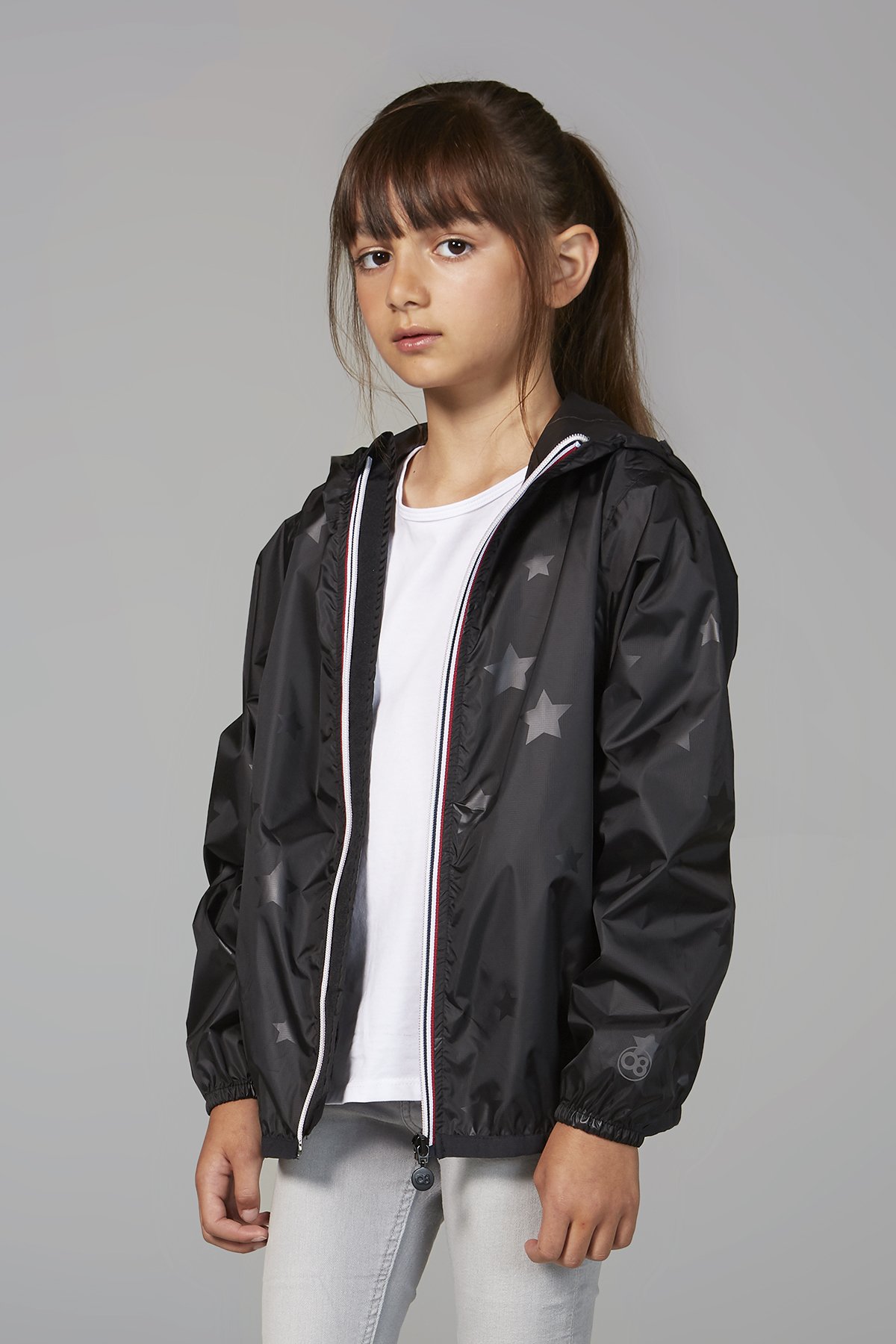 Kids black gloss stars packable rain jacket, showcasing its stylish design and practical features.