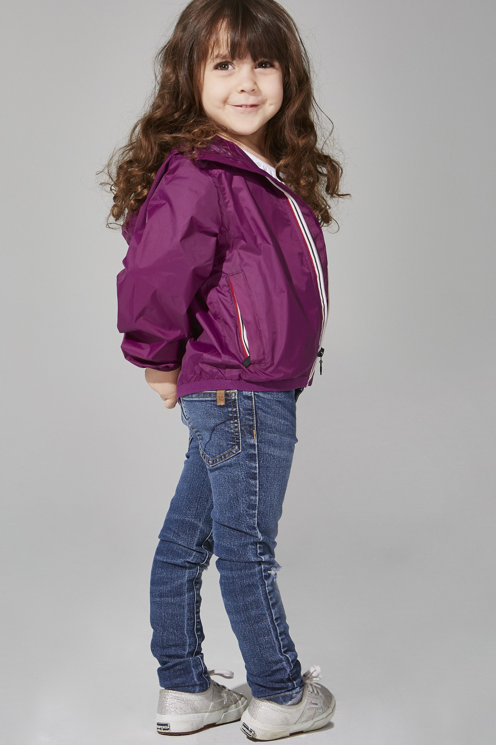 Kids Grape Full Zip Packable Rain Jacket displayed on a hanger, showcasing its vibrant color and full-zip design.