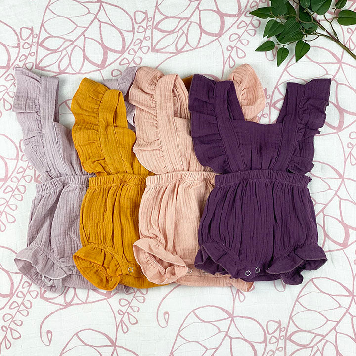 A stylish linen ruffle romper in plum color with ruffled straps and leg openings, featuring a tie closure at the back.