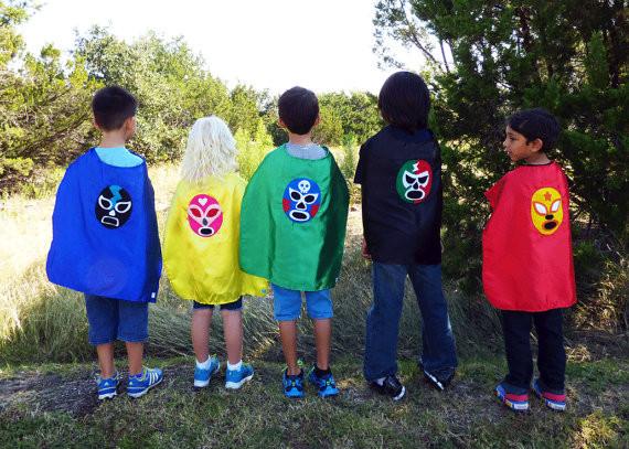 A vibrant pink Mexican wrestler cape, handmade with felt appliqué designs, perfect for children to play superhero.