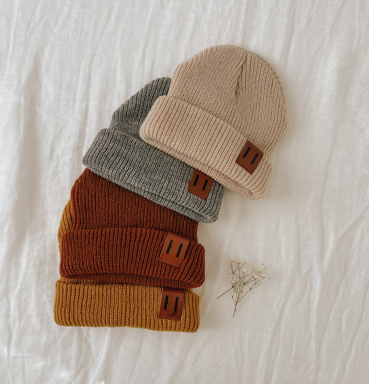 A soft and stylish neutral knit bonnet for babies, designed to fit ages 6M to 18M, featuring a secure brown tag.