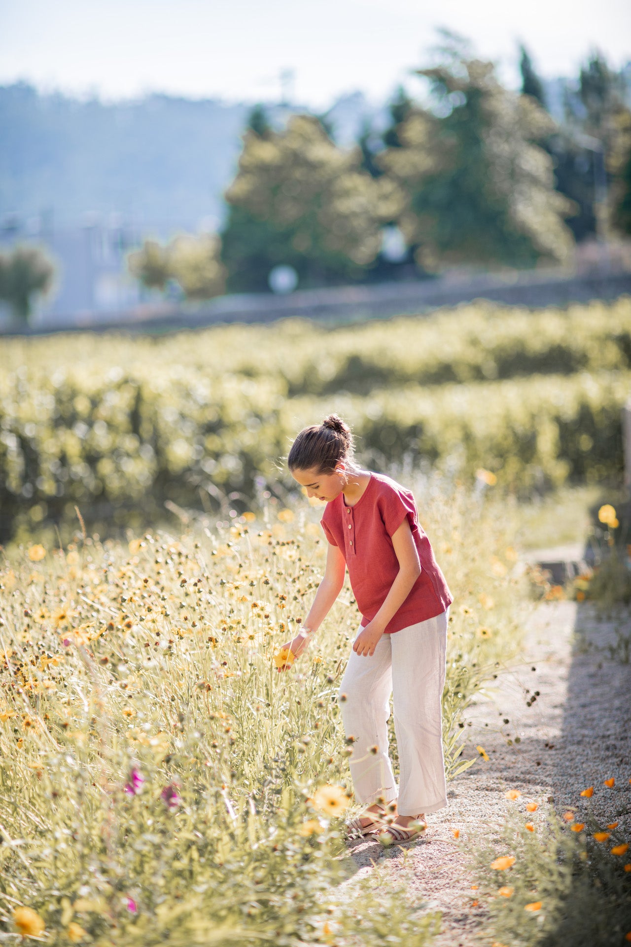 Aster Creme Pants featuring a straight leg design, wood buttons on the sides, and an elasticised waist, made from 100% breathable linen.