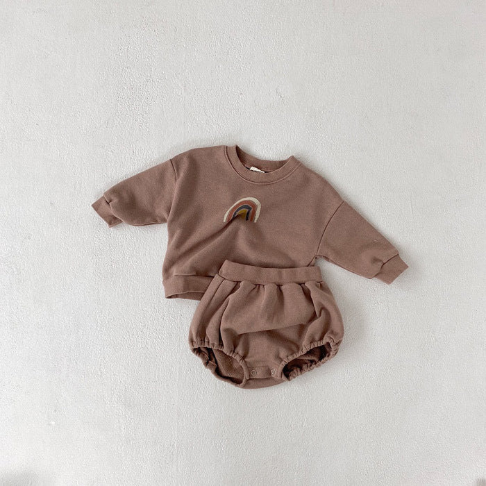 A cozy rainbow 2 pc sweatshirt set in toast color featuring a vintage rainbow design on the sweatshirt and bubble shorts with elastic waistband.